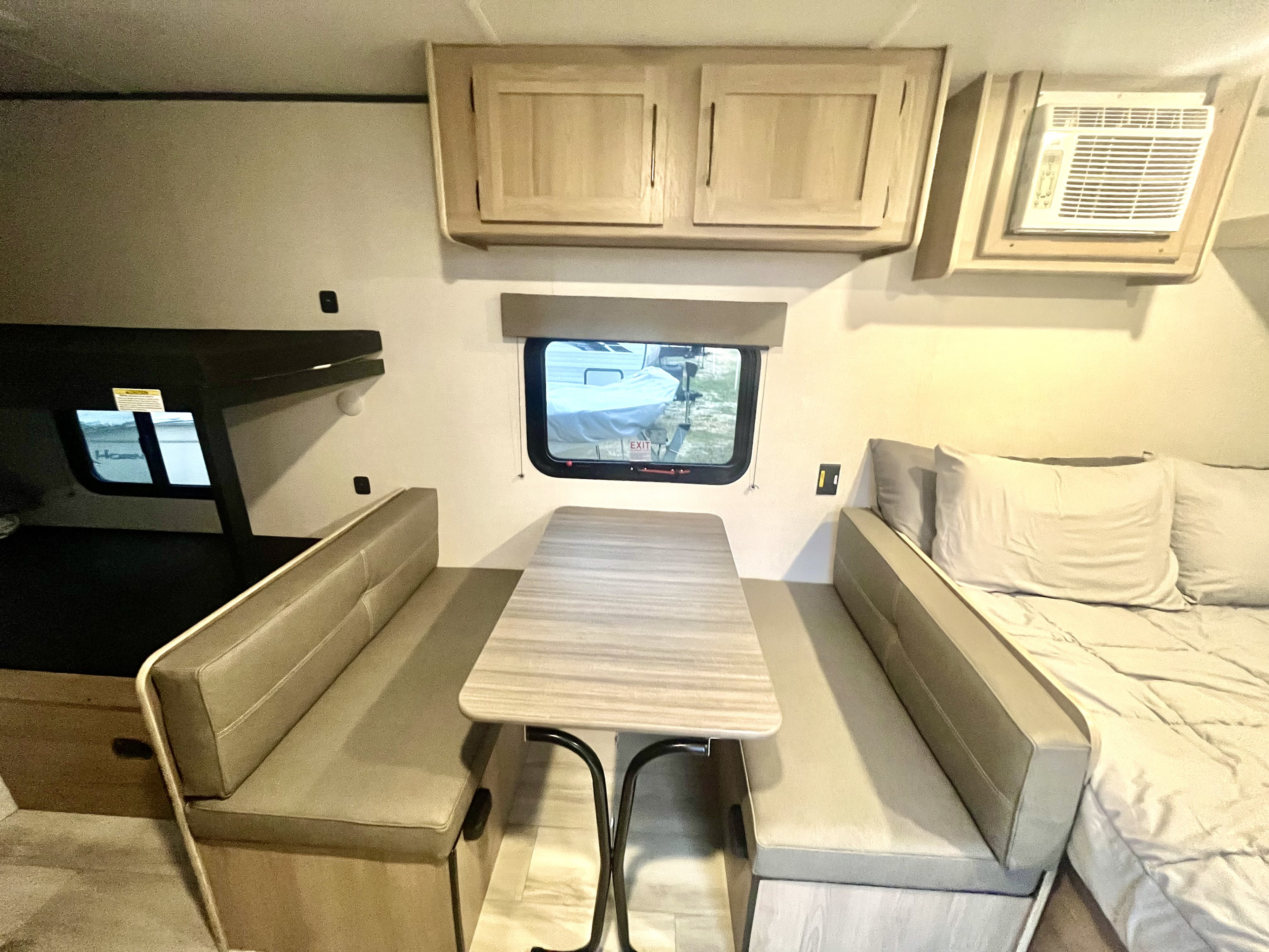 Spacious RV rental interior: a bright living space with a dinette, bunk beds, a large bed, and overhead cabinets.. Coleman Other 2025
