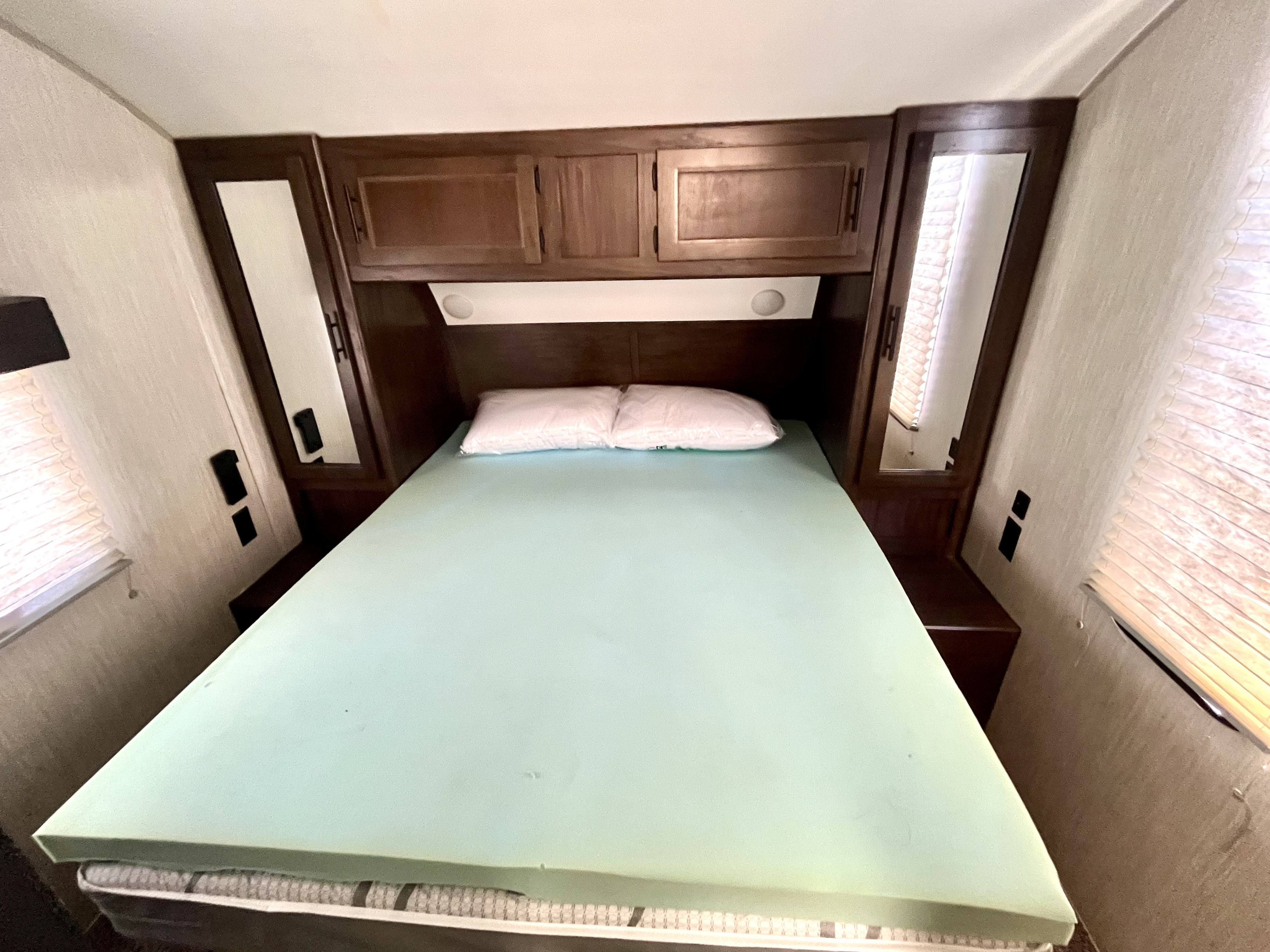This RV rental bedroom features a queen bed with a memory foam topper, overhead storage, and mirrored closets for a comfortable stay.. Forest River Cherokee 2020