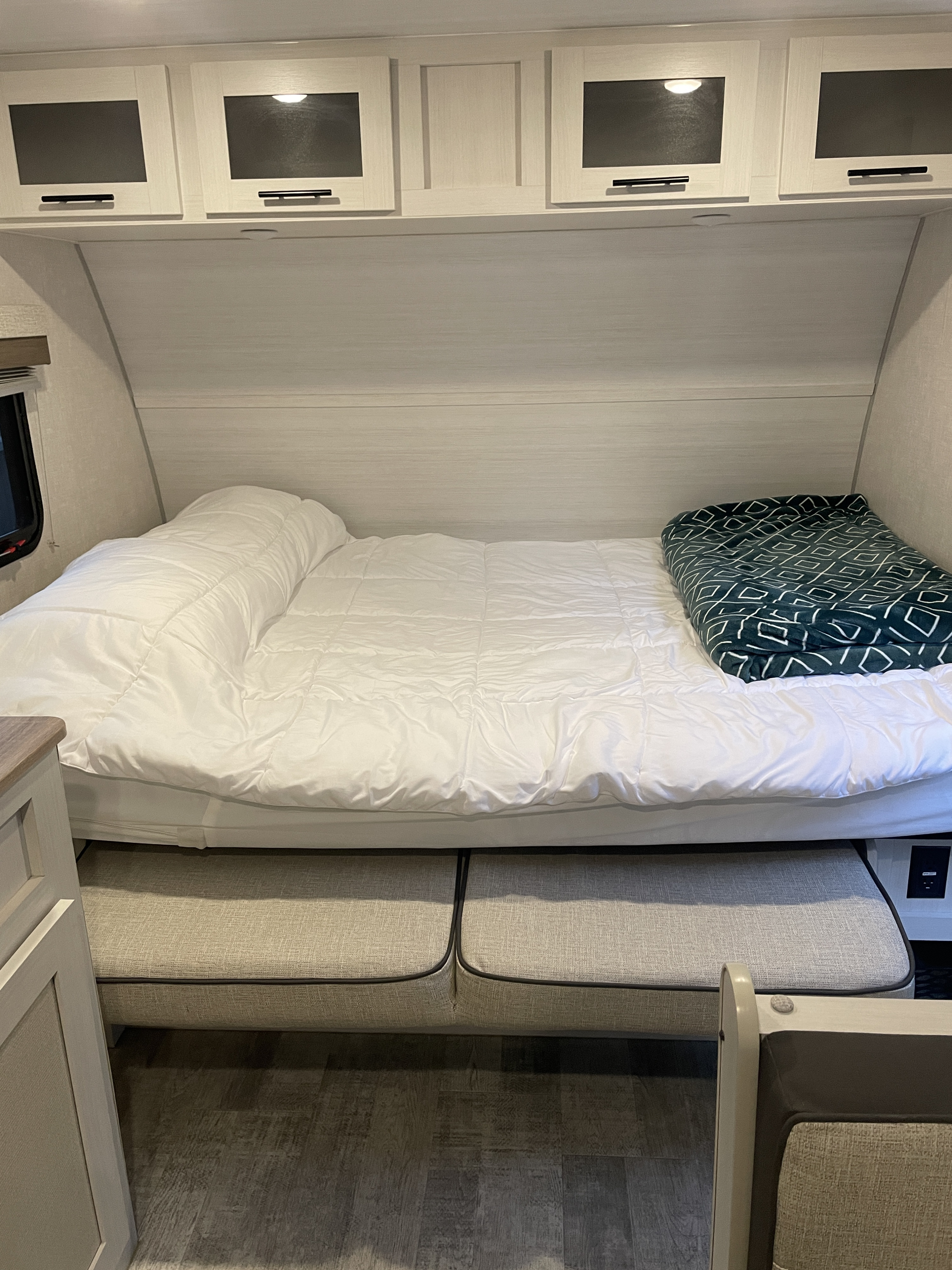 Comfortable RV rental bedroom with a cozy bed, overhead cabinets, and convertible dinette seating.. No Boundaries NoBo 19.3 Essentials Only 2024