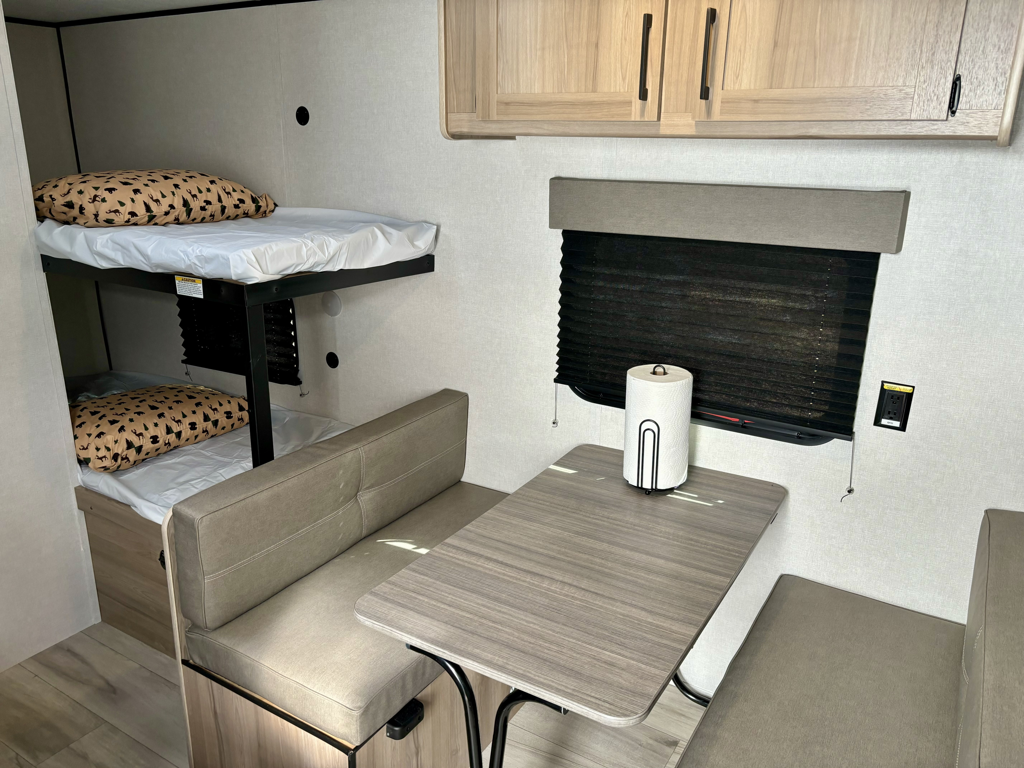 RV rental interior: bunk beds, dinette with table, overhead cabinets, and light wood tones.. Coleman 17B 2025