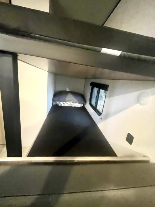 Compact bunk bed area in an RV rental, offering a cozy sleeping space with a small window. Ideal for camper travel.. Keystone Coleman 20 2025
