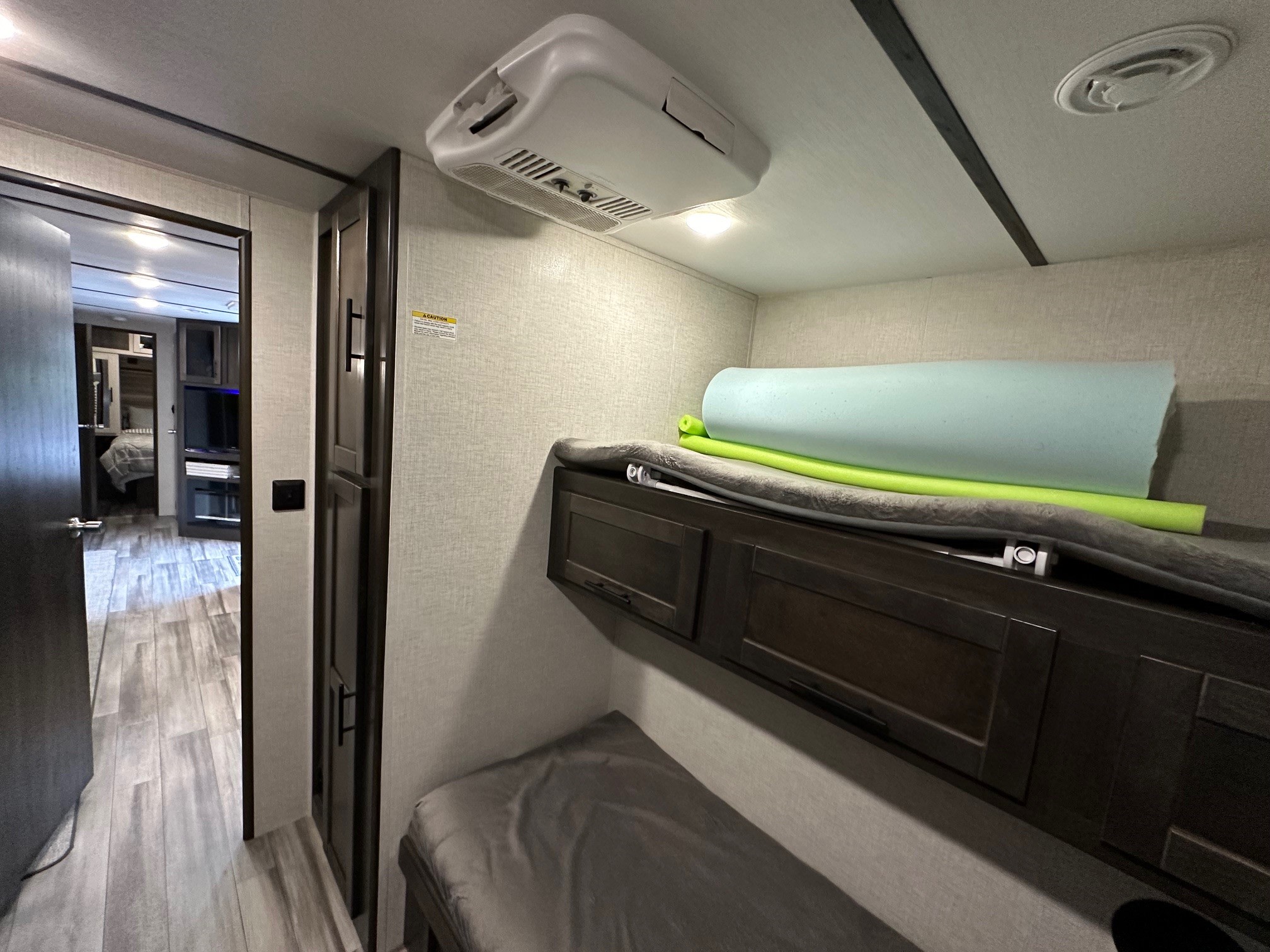Spacious RV rental interior: bunk beds, wood cabinets, ceiling AC, and hallway leading to a bedroom.. Crossroads RV Cruiser Aire 2022