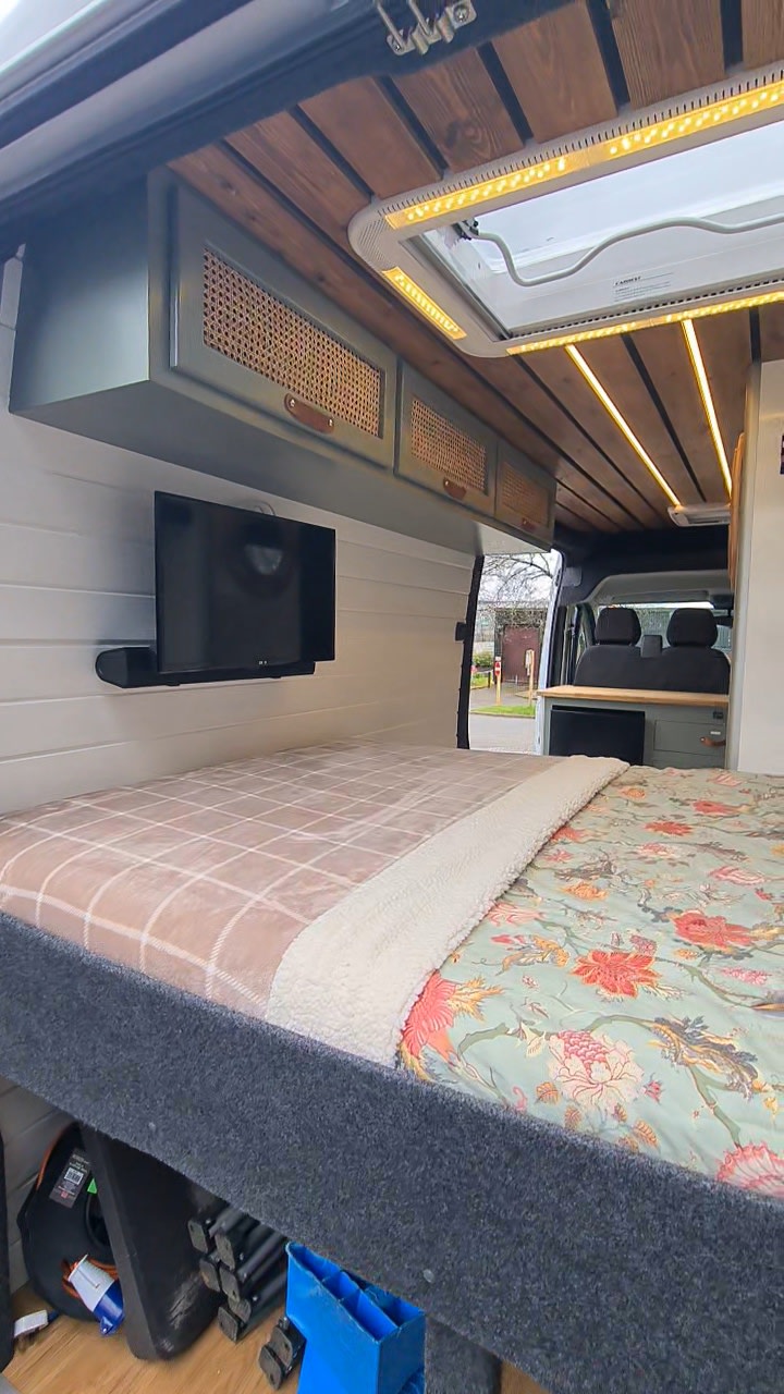Modern camper van bed setup for rv rental, featuring a mounted TV, chic overhead storage, and wooden ceiling with lights.. Citroen Relay L3H2 2022