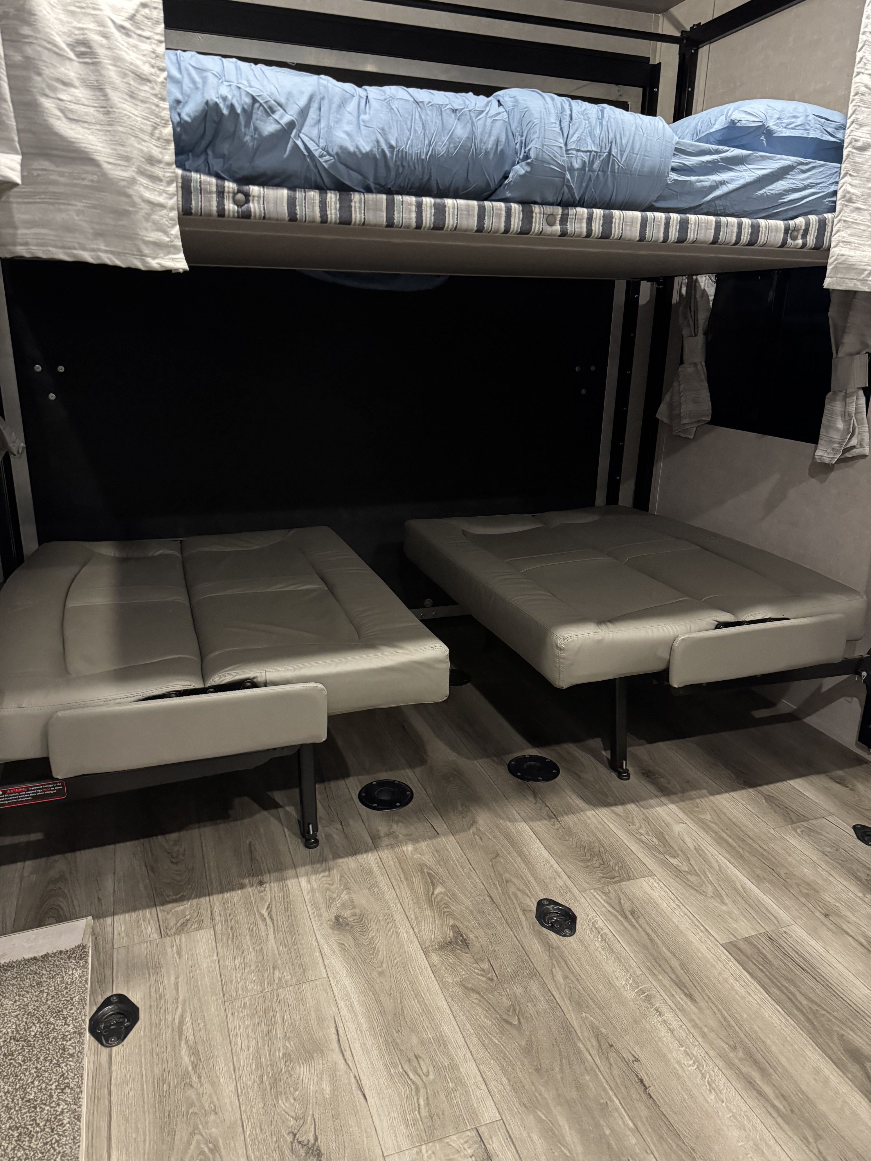 Inside an RV rental: a top bunk with blue bedding and two lower convertible sofa beds, great for travel.. Eclipse Attitude Limited Toy Hauler 2023
