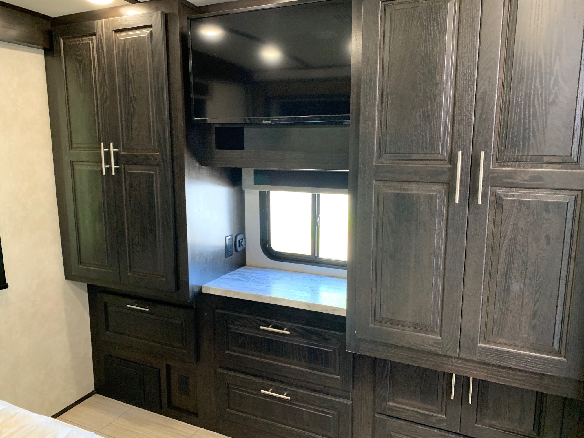 Explore this RV rental's well-equipped bedroom: dark wood cabinets, drawers, counter space, and a TV for your comfort.. Forest River Fr3 2021