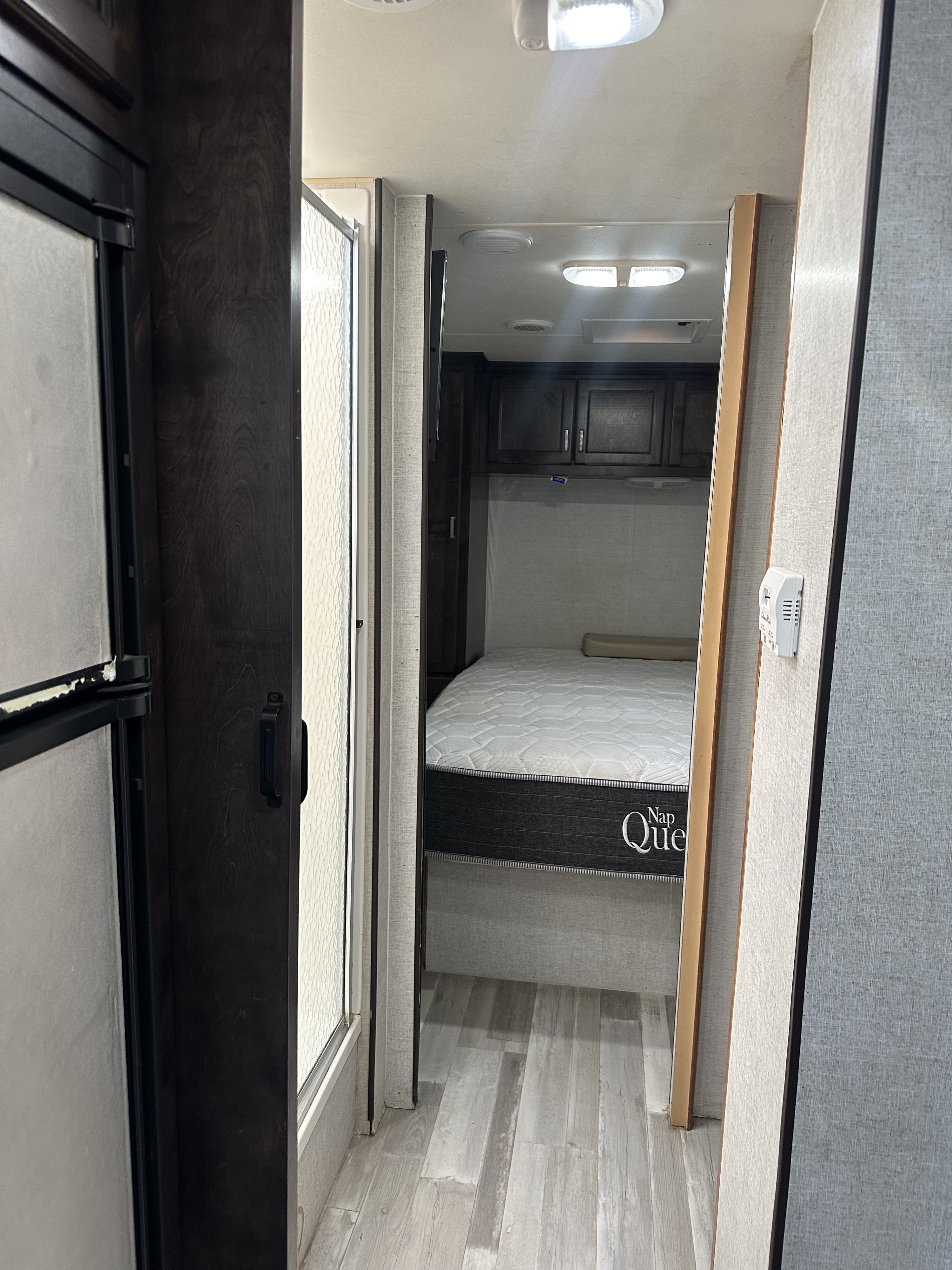 RV rental interior: cozy bedroom with a Nap Queen mattress, compact shower, and smart living space layout.. Winnebago Minnie Winnie 2015