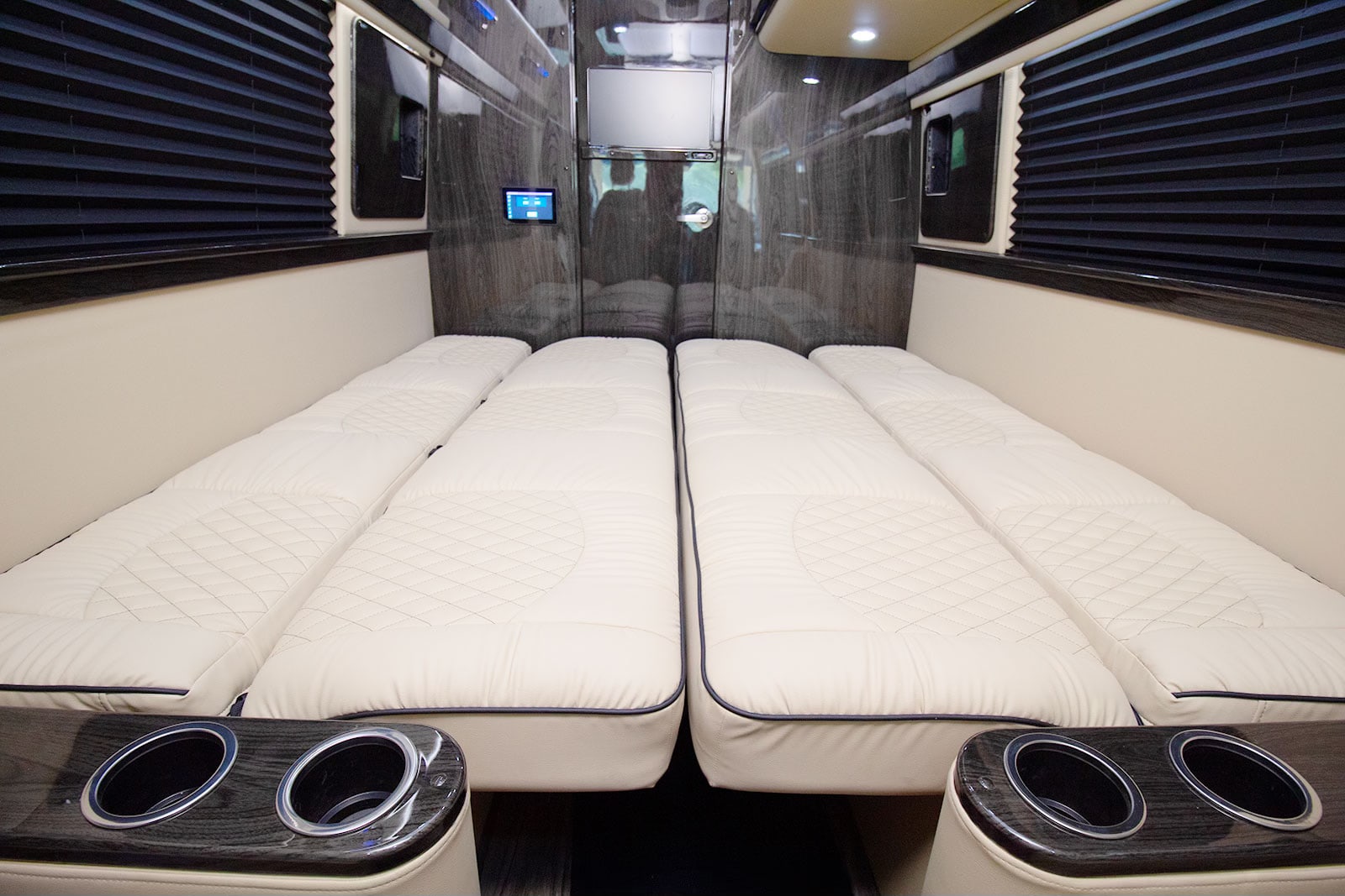 Comfortable interior of an RV rental: two plush beds, wood paneling, cup holders, & window blinds visible.. Ultimate Ultimate RV 2025