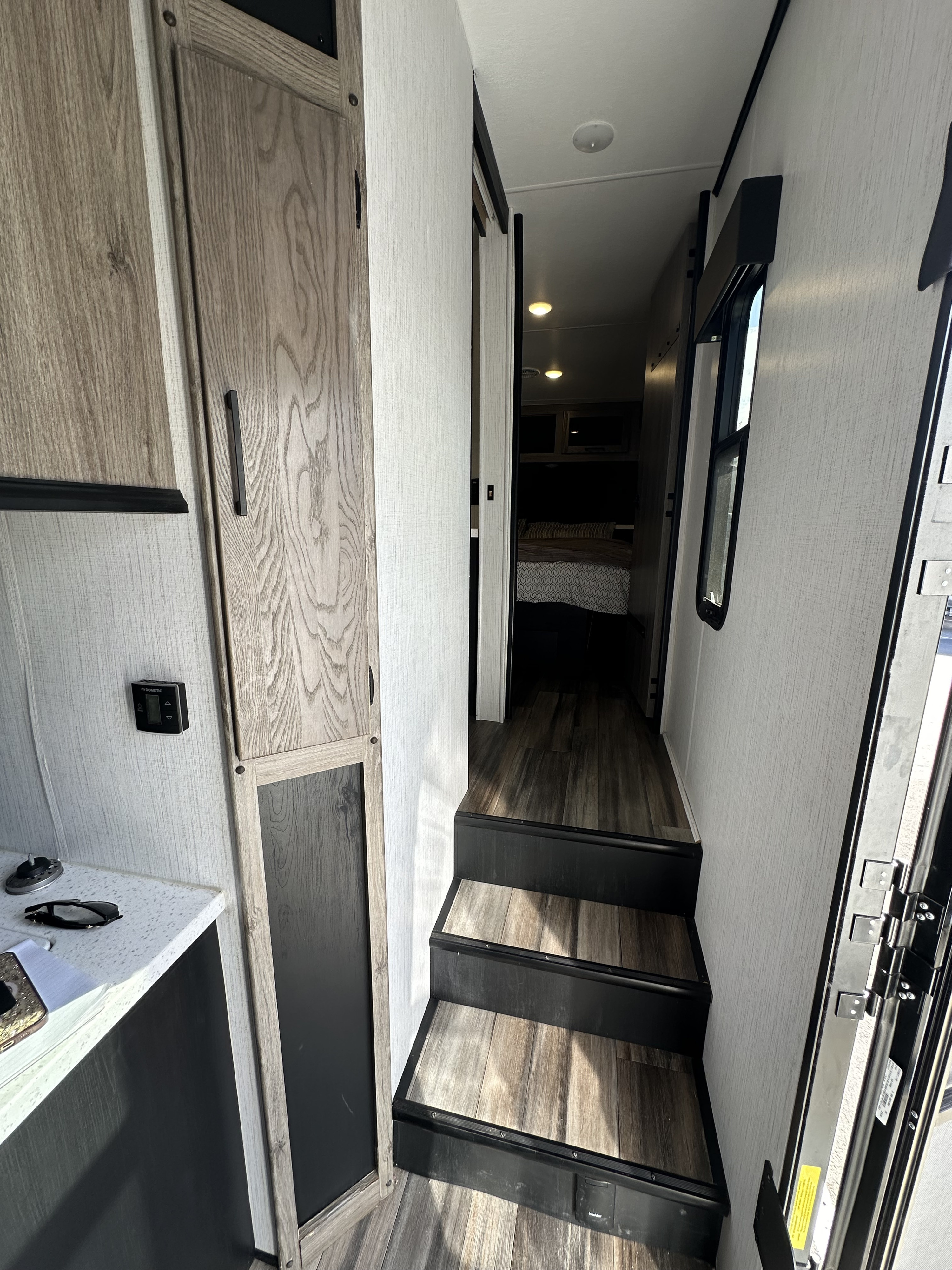 RV rental interior: steps lead to a hallway with a window, connecting to the bedroom. A counter is visible left.. Heartland RVs Road Warrior Toy Hauler 2022