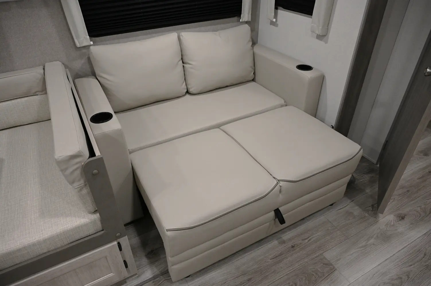 RV rental comfort: A cream pull-out sofa with cup holders, extended for a footrest or sleeping area.. Coachmen Catalina Legacy 2021