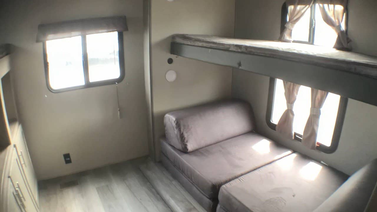 RV rental interior with comfortable bunk beds & a convertible sofa, offering bright sleeping/seating space.. Coachmen Catalina 2024