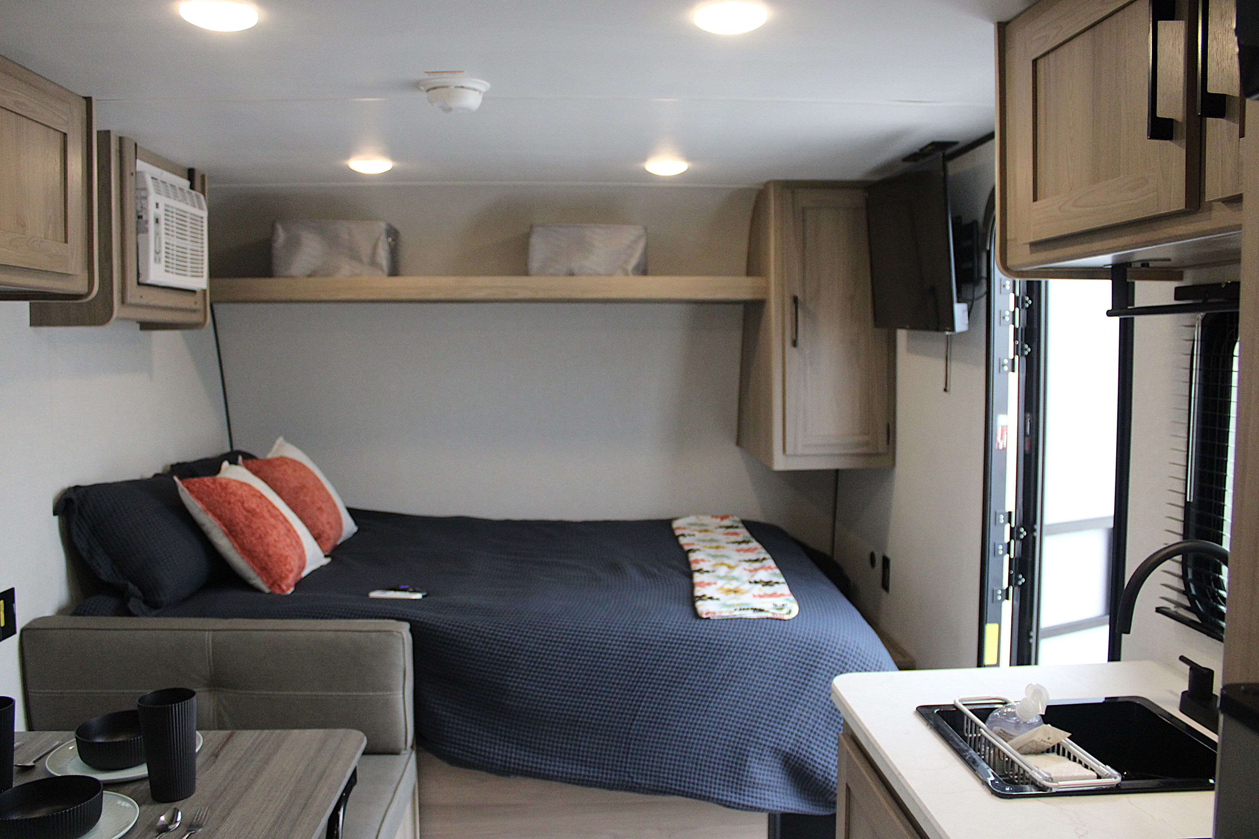 Cozy RV rental interior shows a compact bedroom, kitchen, and dining area, designed for comfortable travel.. Keystone RV Coleman 17B 2025