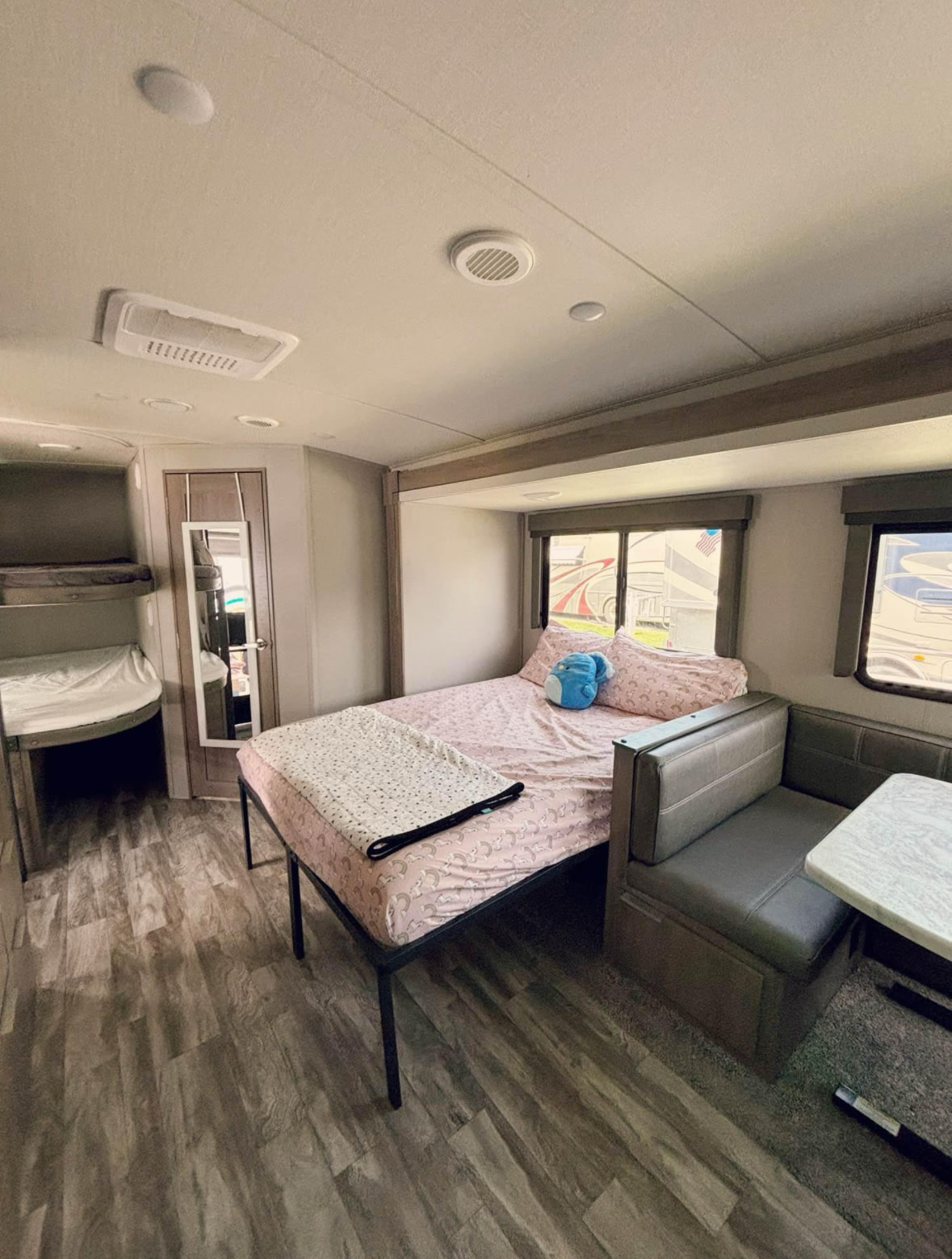 RV rental interior featuring a bed with pink sheets, bunk beds, and a dinette. Comfortable space for travel.. Grand Design Imagine 2021