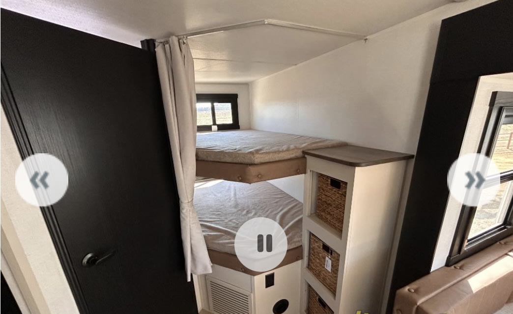 This RV rental features a cozy bunk bed area with two mattresses, a privacy curtain, and built-in storage baskets.. Forest river Heritage glen 2025