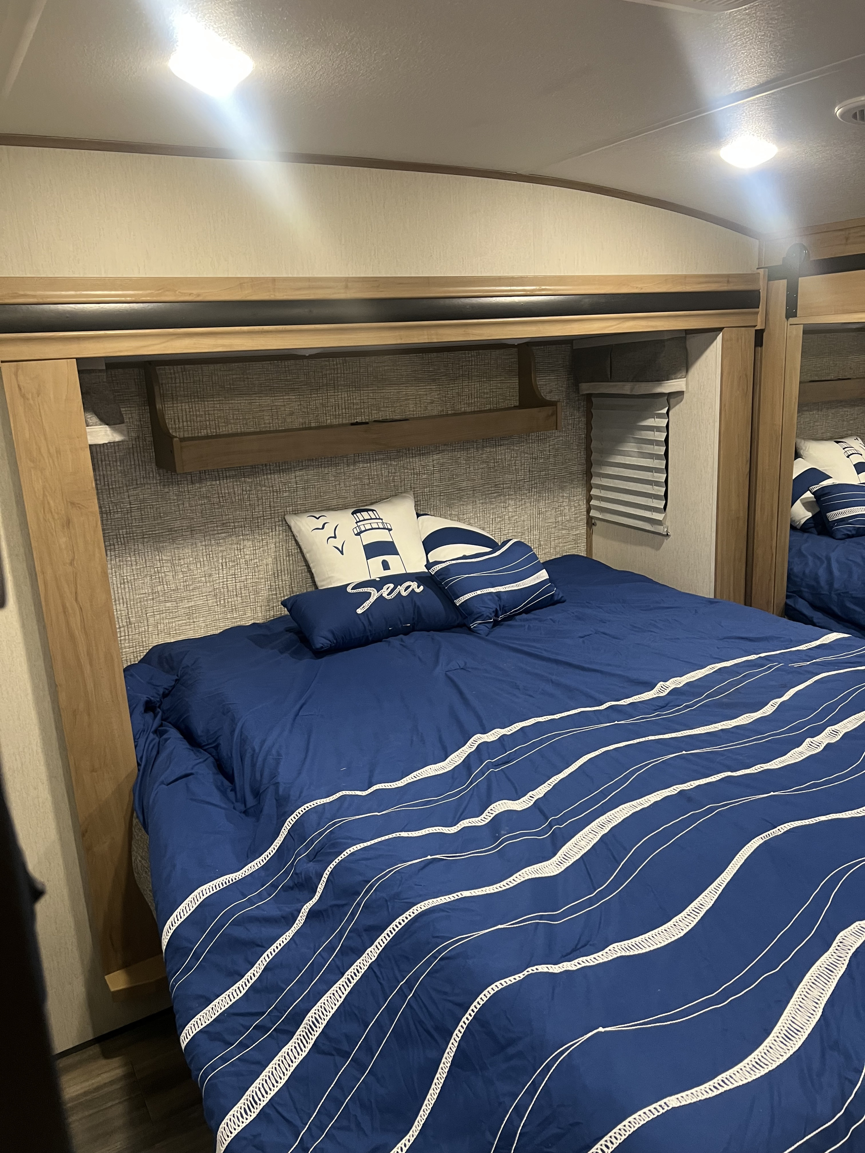 Bright RV rental bedroom: navy blue nautical bedding, themed pillows, and built-in storage.. Forest River Sabre 2024