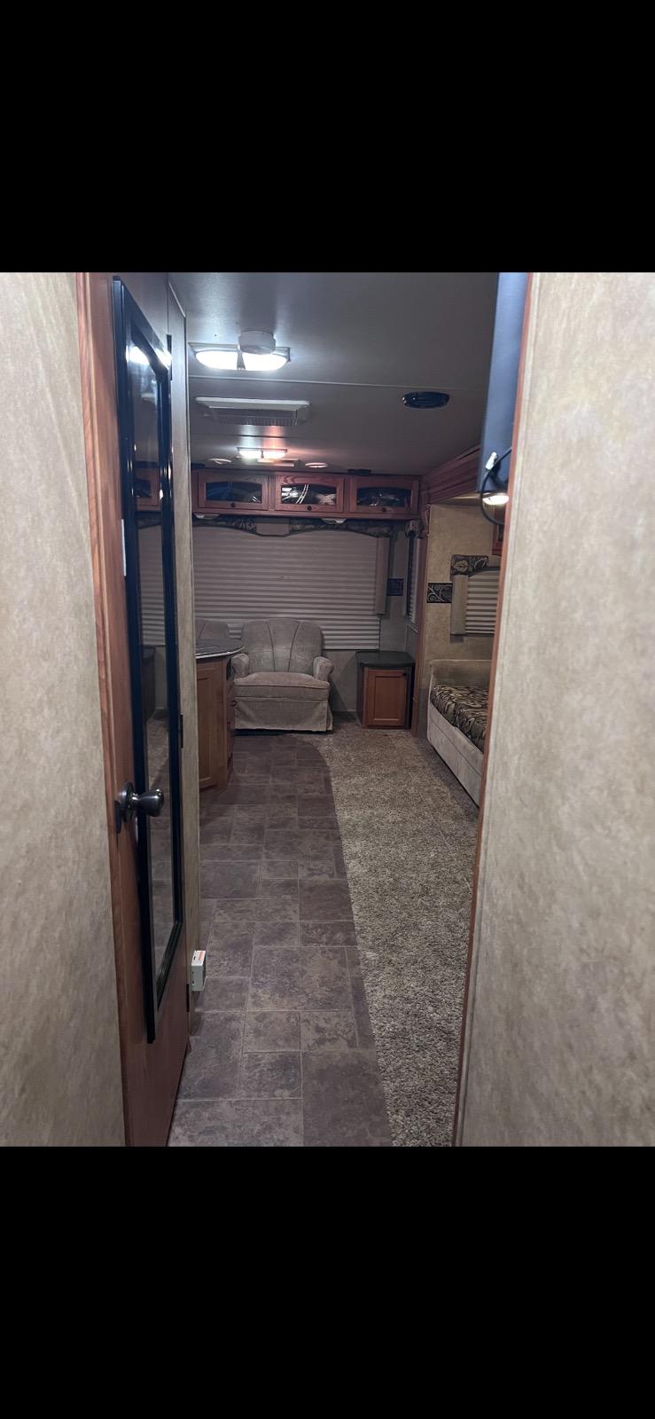 Cozy RV rental interior: a view down the aisle showing an armchair, cabinets, and a bench seat with patterned cushions.. Heartland RVs North Trail 2011
