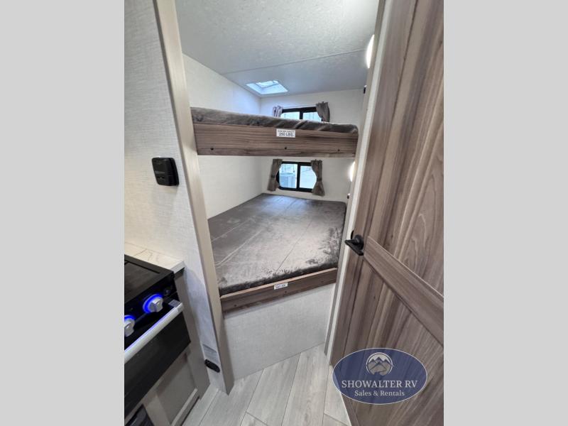 RV rental interior featuring comfortable bunk beds with windows, a compact kitchen, and wooden door, maximizing space.. K-Z Manufacturing Connect Mini 231BH 2025
