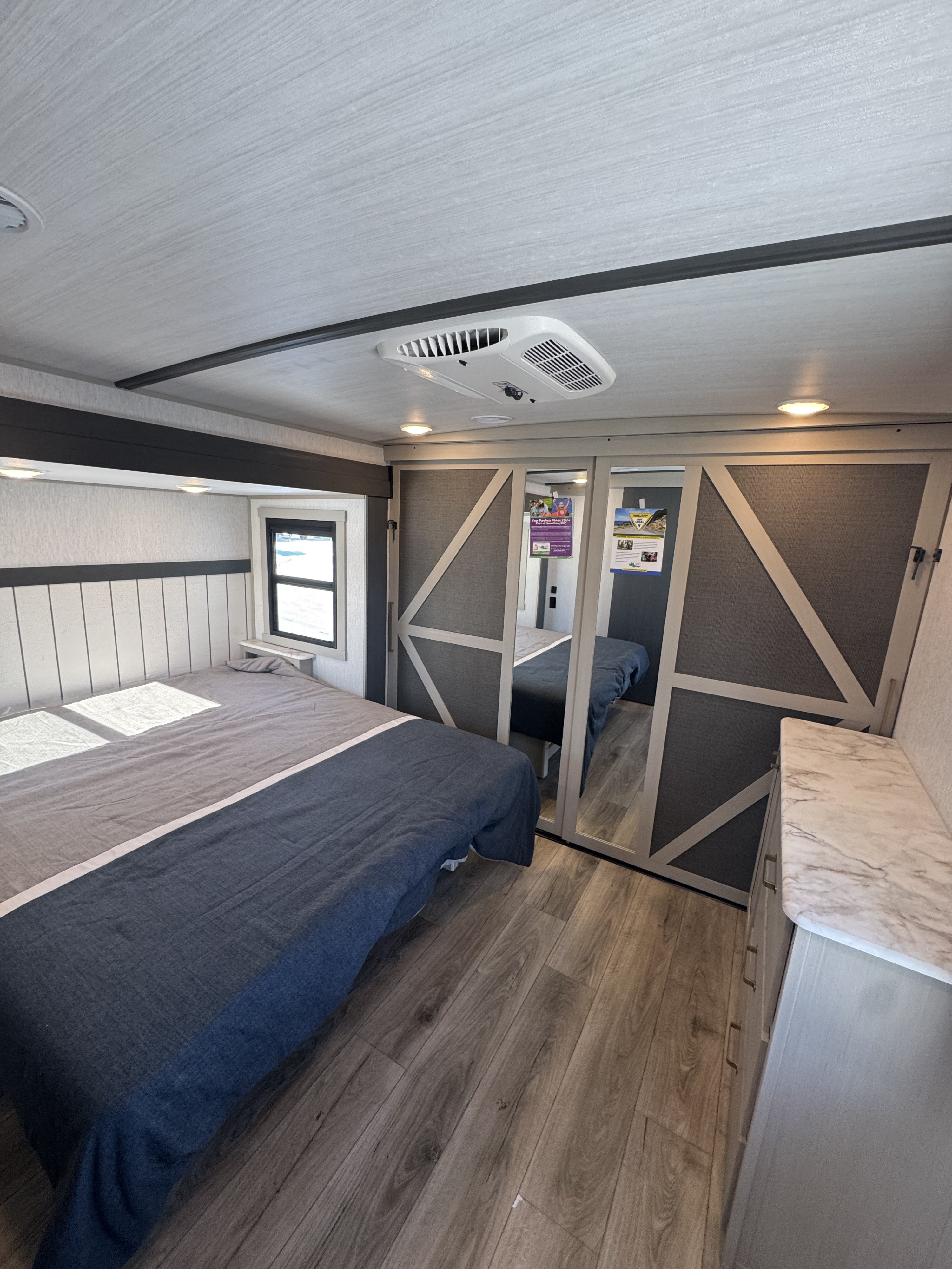 Modern RV rental bedroom with stylish bedding, AC, mirrored closets, and wood-look flooring.. Forest River Salem Hemisphere 2024