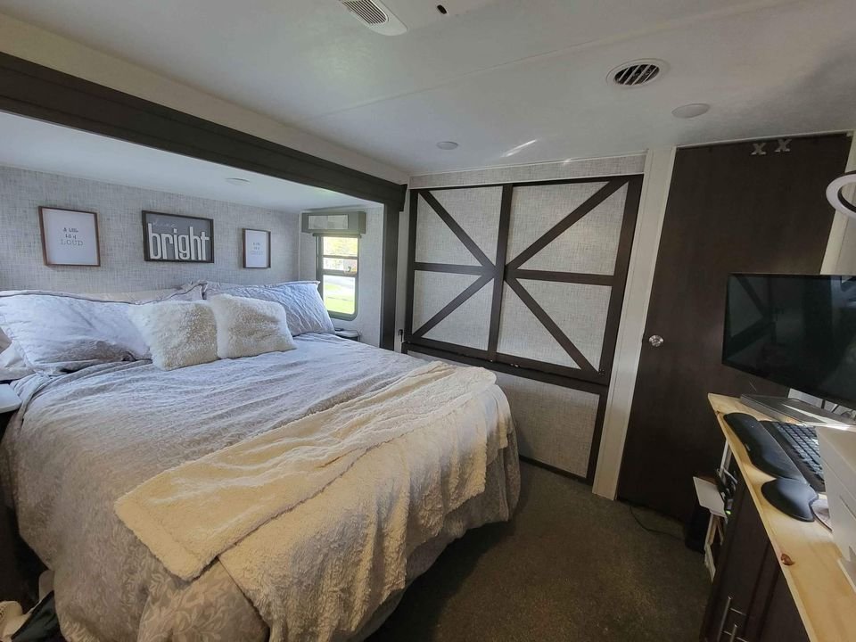 Inside a cozy RV rental bedroom: a large bed, decorative wall art, built-in storage, and a desk for your travel needs.. Forest River Salem 2018