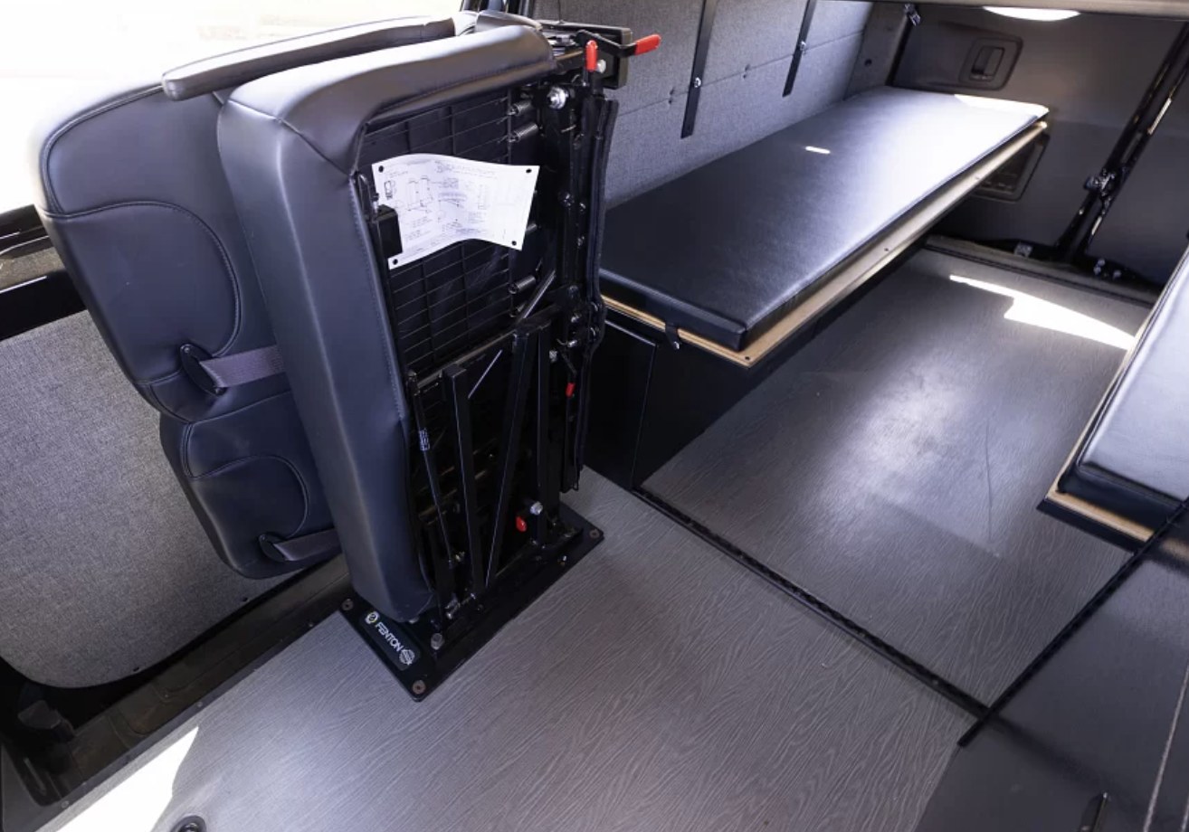 Versatile RV rental interior shows a black foldable seat and a long padded bench/bed, maximizing space for travel.. Vanworks Switchback 4D 144 2022