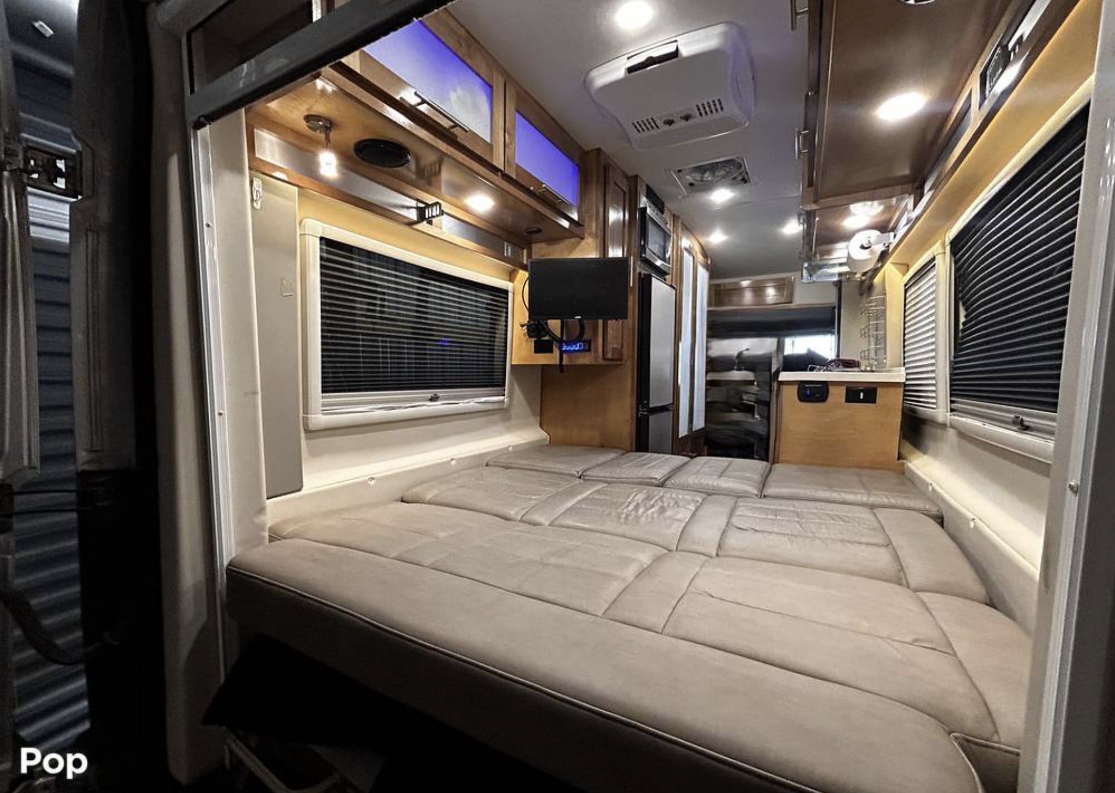 Inside an **rv rental**: a cozy bed with window blinds, compact kitchen, and overhead storage. Perfect for travel adventures.. Coachmen Beyond 2020
