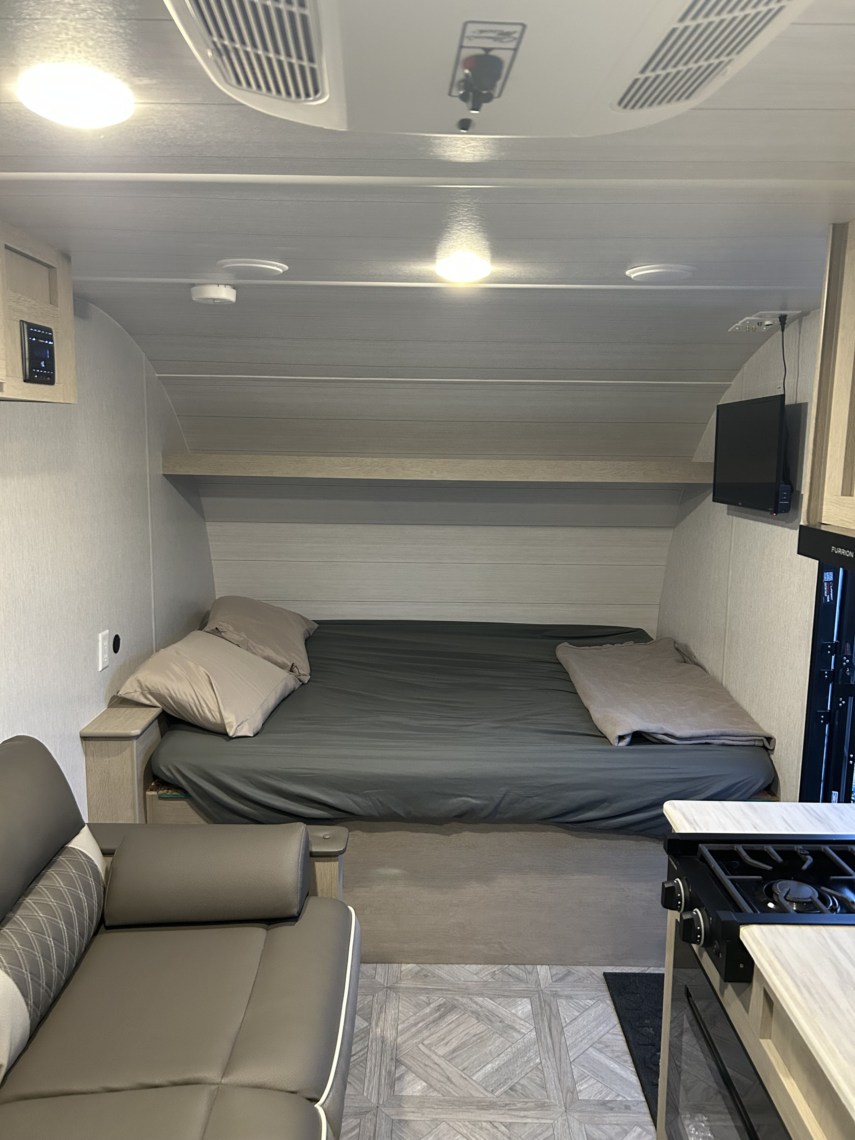 Cozy RV rental interior showing a bed, sofa, and compact kitchen. Ideal for road trips, offering comfortable living space.. Forest River Wildwood Select 2024