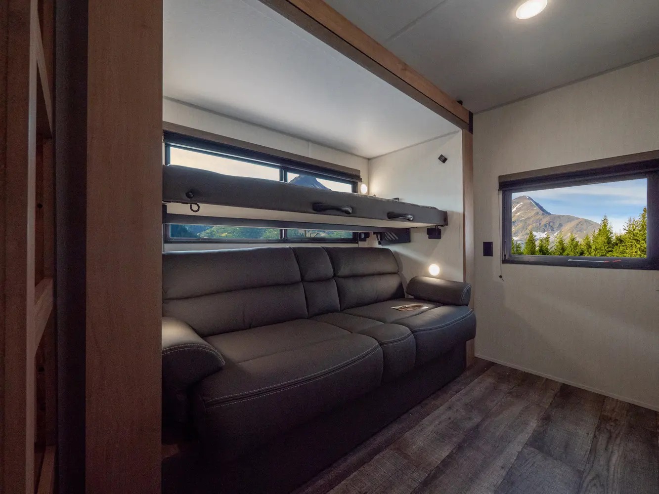 Cozy RV rental interior with sofa, bunk bed, and scenic mountain views. Ideal for travel adventures.. Forest River Campsite Reserve 2025