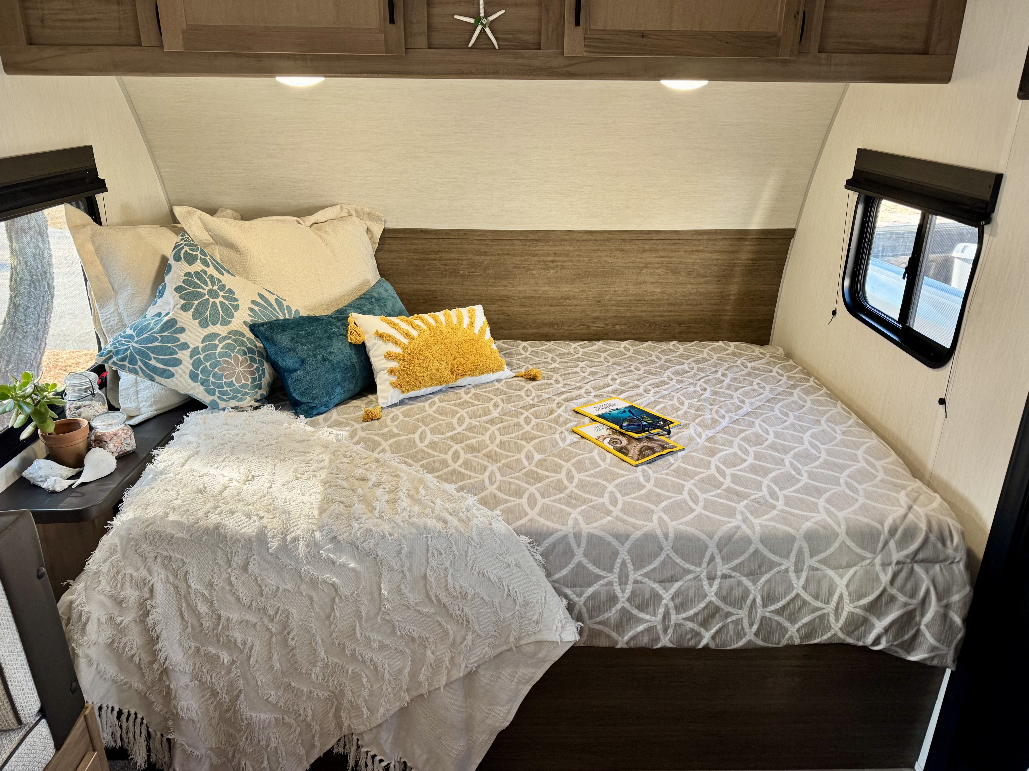 Step into this inviting RV rental bedroom! Plush bedding, beach decor, and reading material await your travels.. Cherokeee Wolf Pup 2025