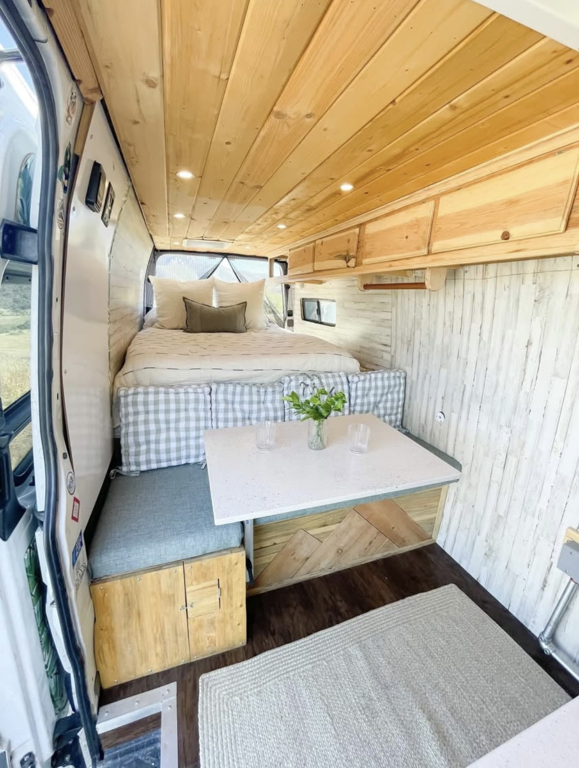 Explore this stylish RV rental! A custom camper van interior featuring a comfortable bed, dining table, & wood decor.. Mercedes-Benz Sprinter 316 2008