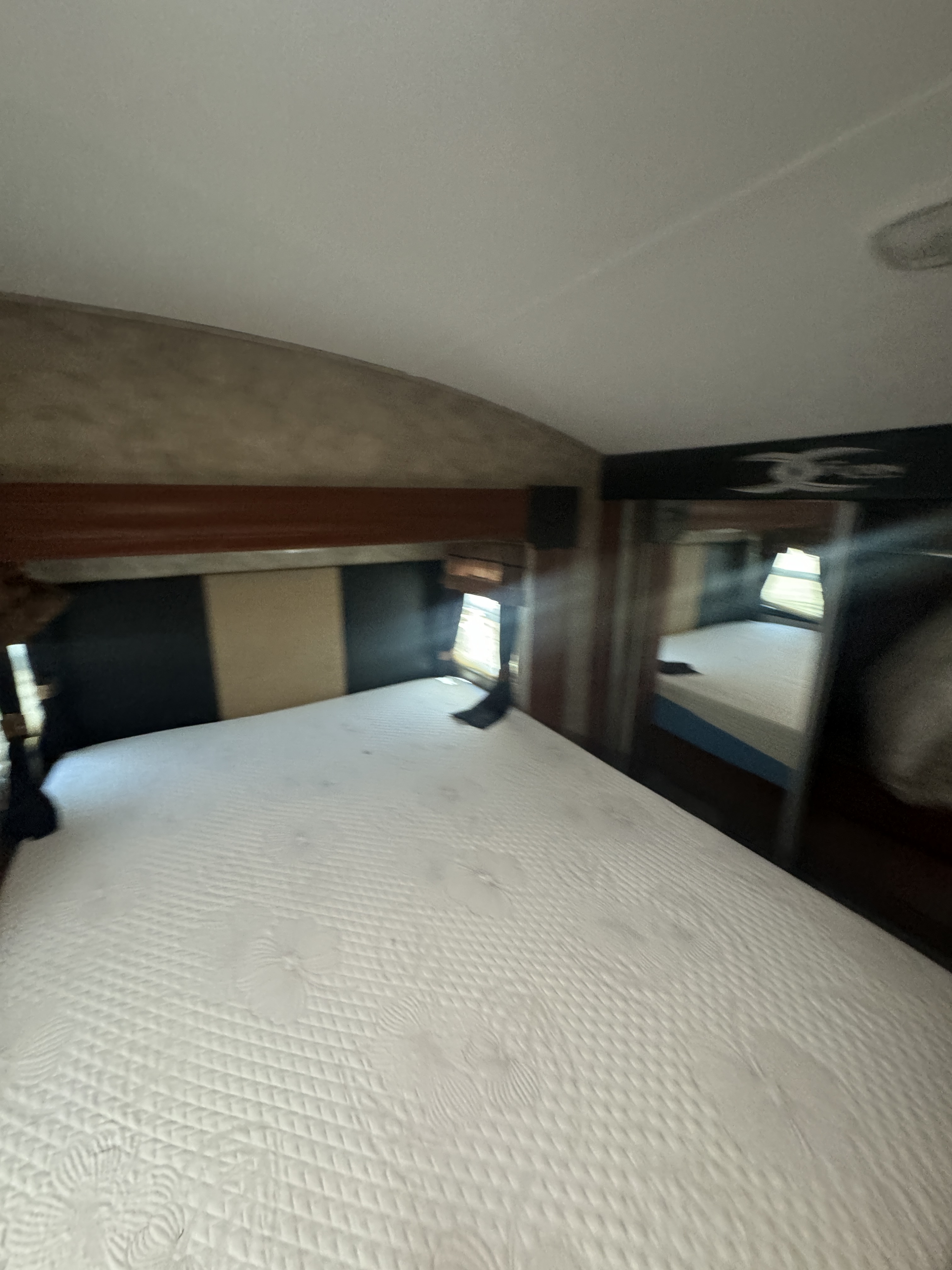 Quilted white mattress in a cozy RV rental bedroom with mirrored storage, ideal for comfortable travel.. Keystone Fuzion 2011