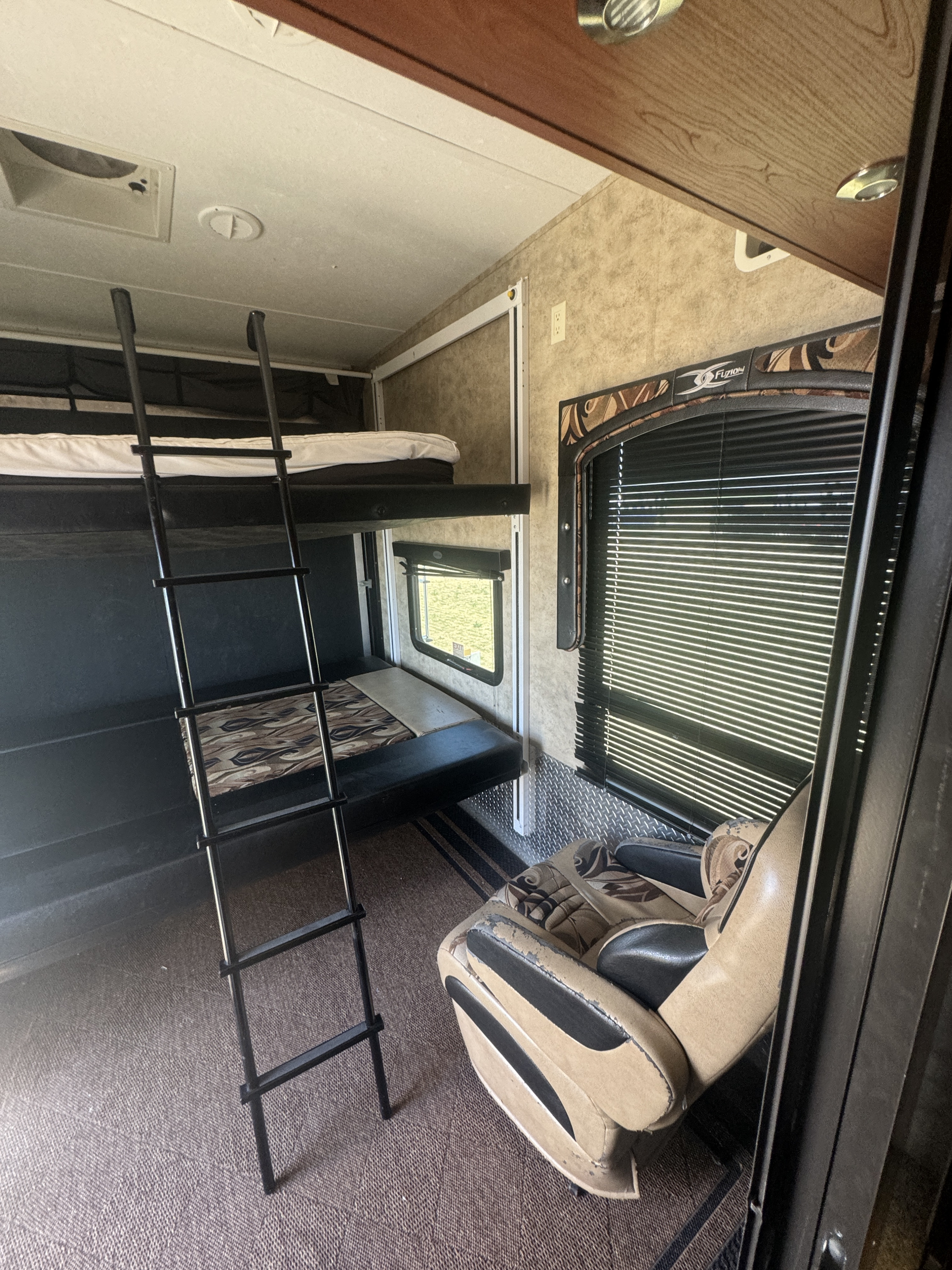 Cozy RV rental interior with bunk beds, ladder, and a recliner, offering versatile sleeping and living space.. Keystone Fuzion 2011