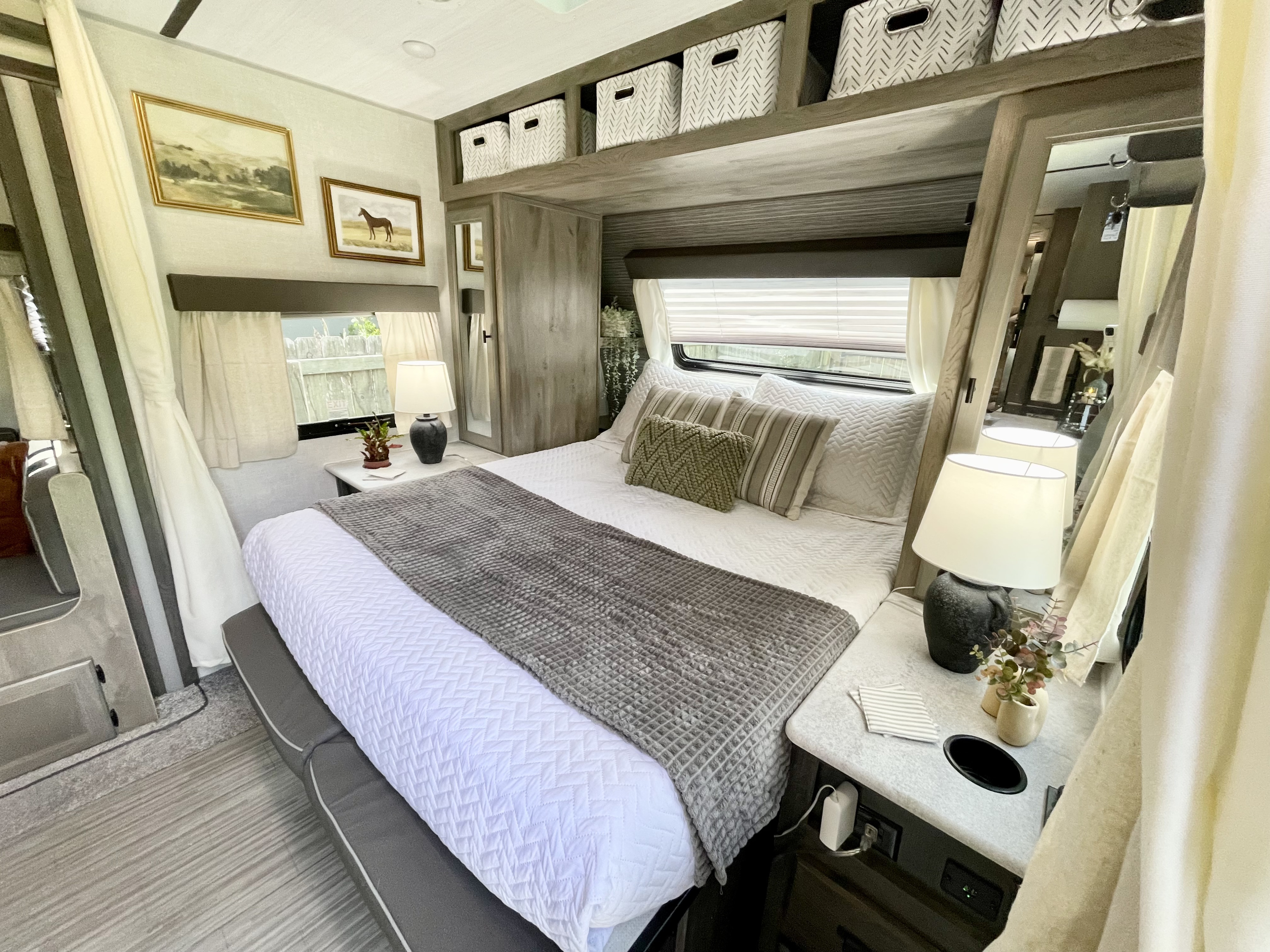 Cozy RV rental bedroom featuring a comfy bed, neutral decor, artwork, and smart overhead storage.. Forest River Surveyor Legend 2021