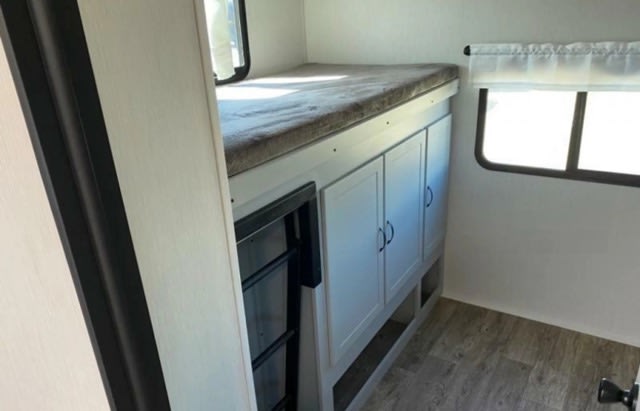 Inside an RV rental: cozy bunk beds with ladder, storage, and a bright window.. Forest River Vibe 2023
