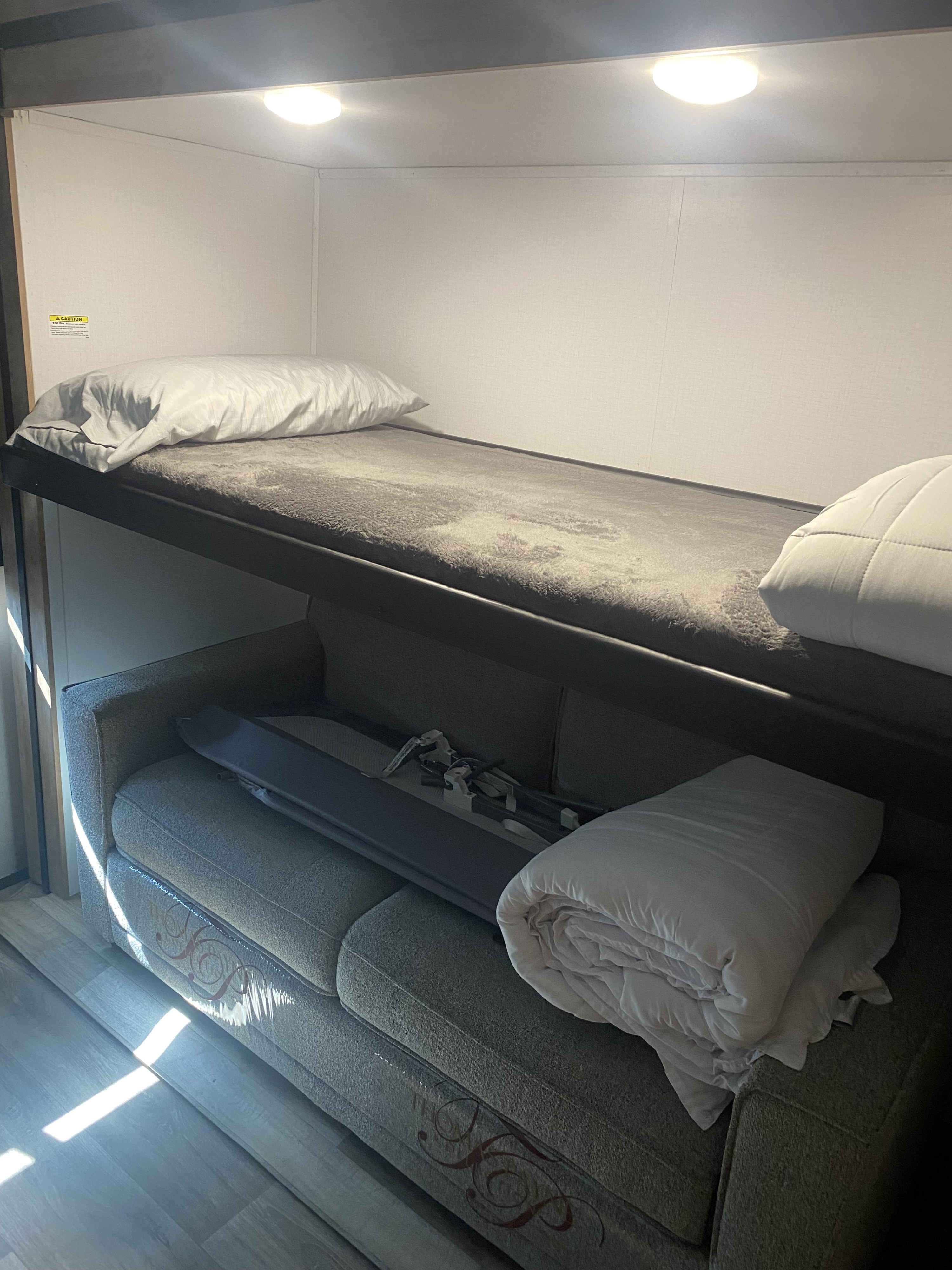 RV rental: Upper bunk with pillow and cozy blanket, overlooking a versatile sofa bed below. Natural light brightens the space.. Keystone RV Outback 2022
