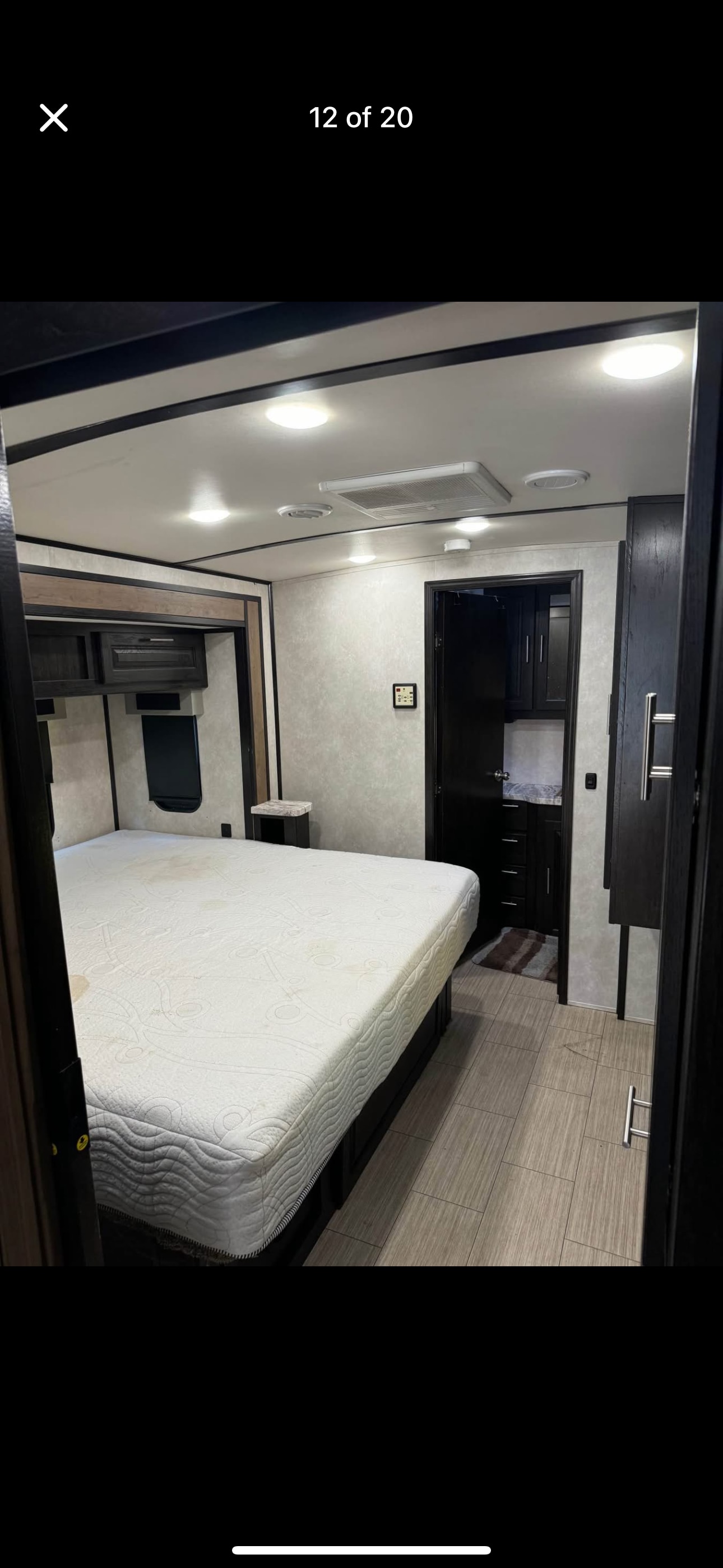 RV rental bedroom: a roomy interior with a stained mattress, nightstand, and adjacent bathroom access.. Forest River FR3 34DS 2020