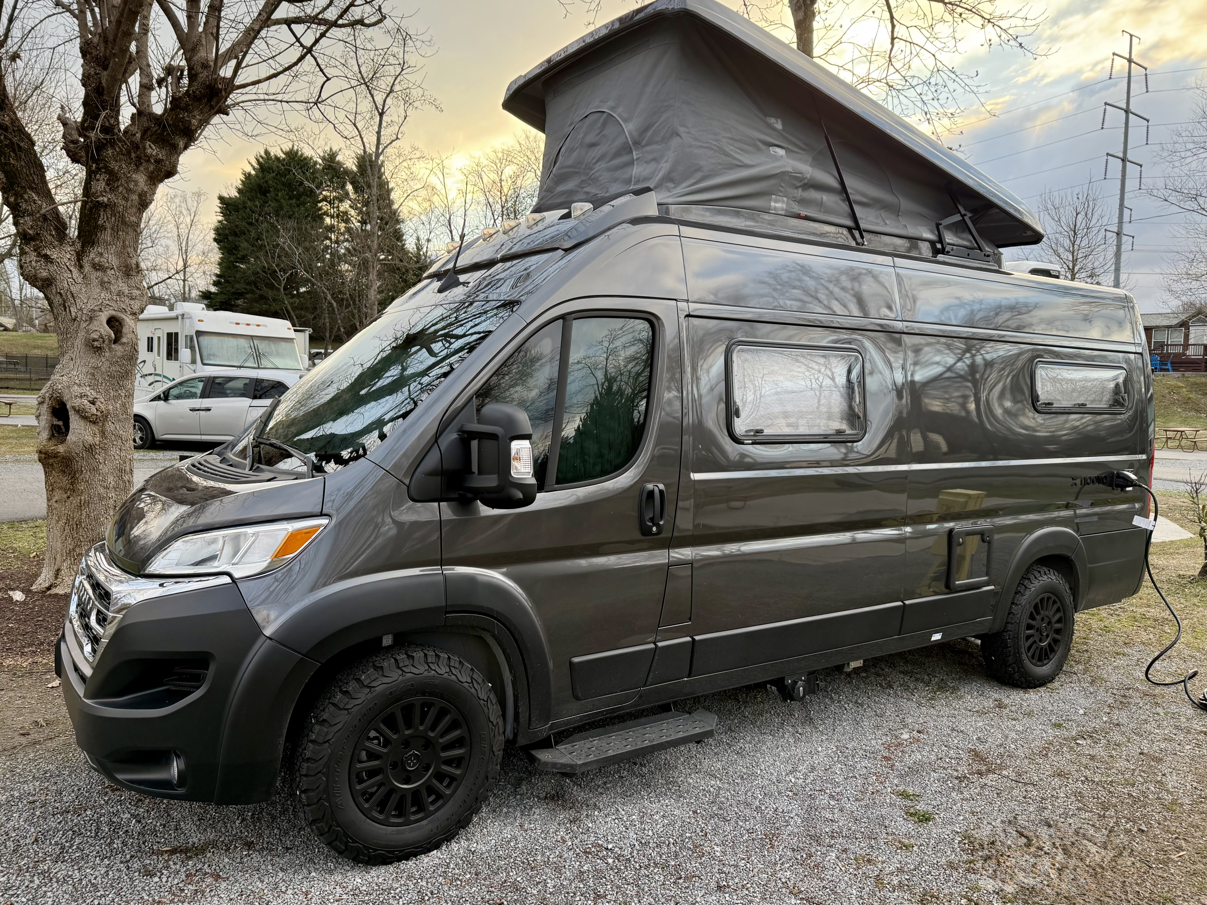 Experience van life travel with this sleek dark grey camper van, featuring a pop-top, ready for your next RV rental camping adventure.. Noovo Pop 2024