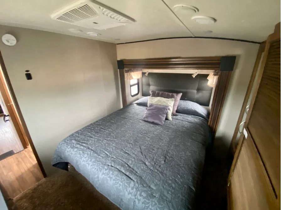 Cozy RV bedroom interior with a queen bed and overhead AC unit, perfect for your next RV rental adventure.. Forest River Chaparral 2018