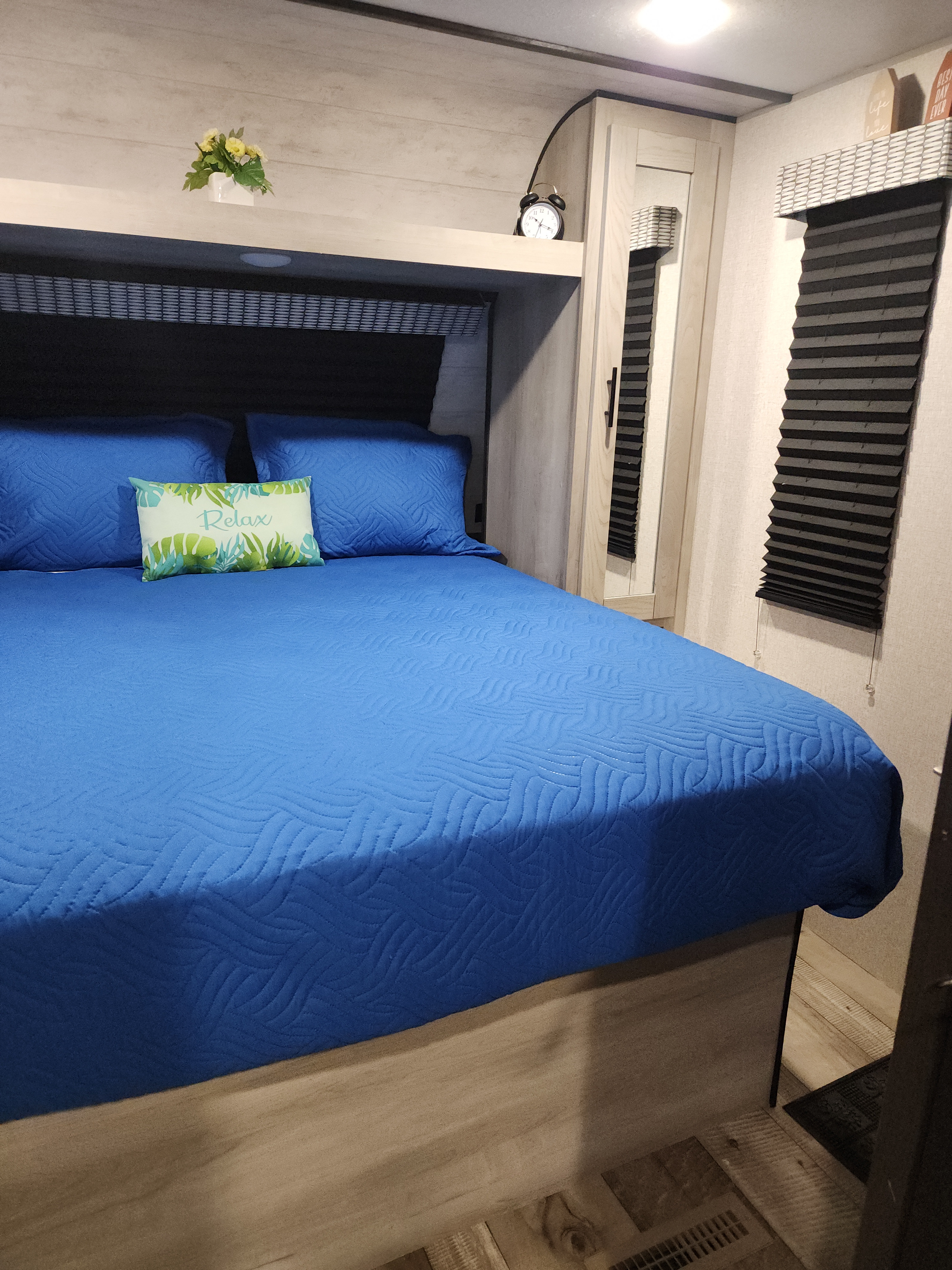 This comfy RV rental bedroom features a vibrant blue bed, "Relax" pillow, and mirrored wardrobe for a great stay.. Connect C-281BHSE 2022