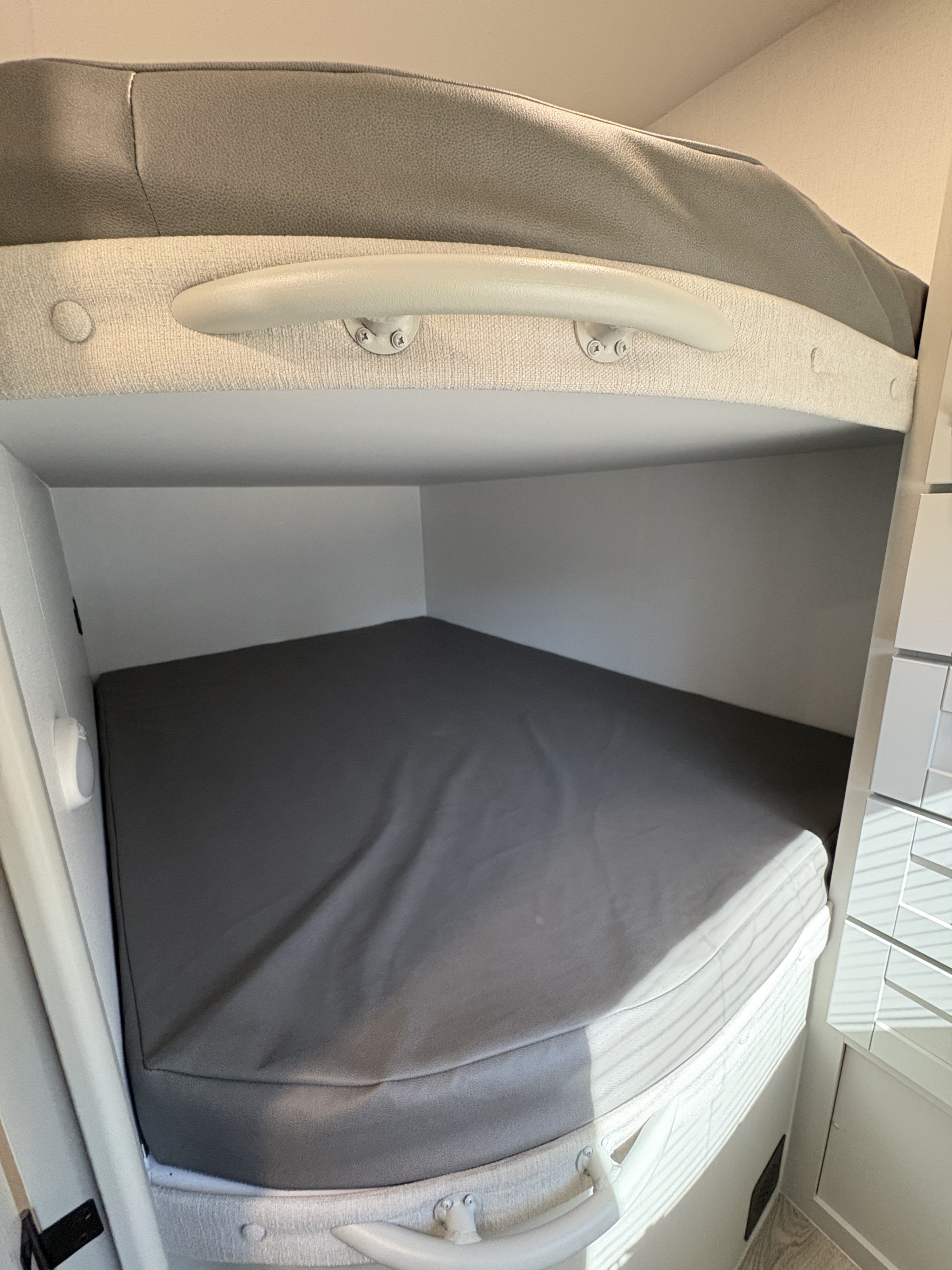 Cozy bunk beds inside an RV rental, featuring comfortable gray mattresses and a safety rail on the upper bunk.. Brinkley 295 AIR 2025
