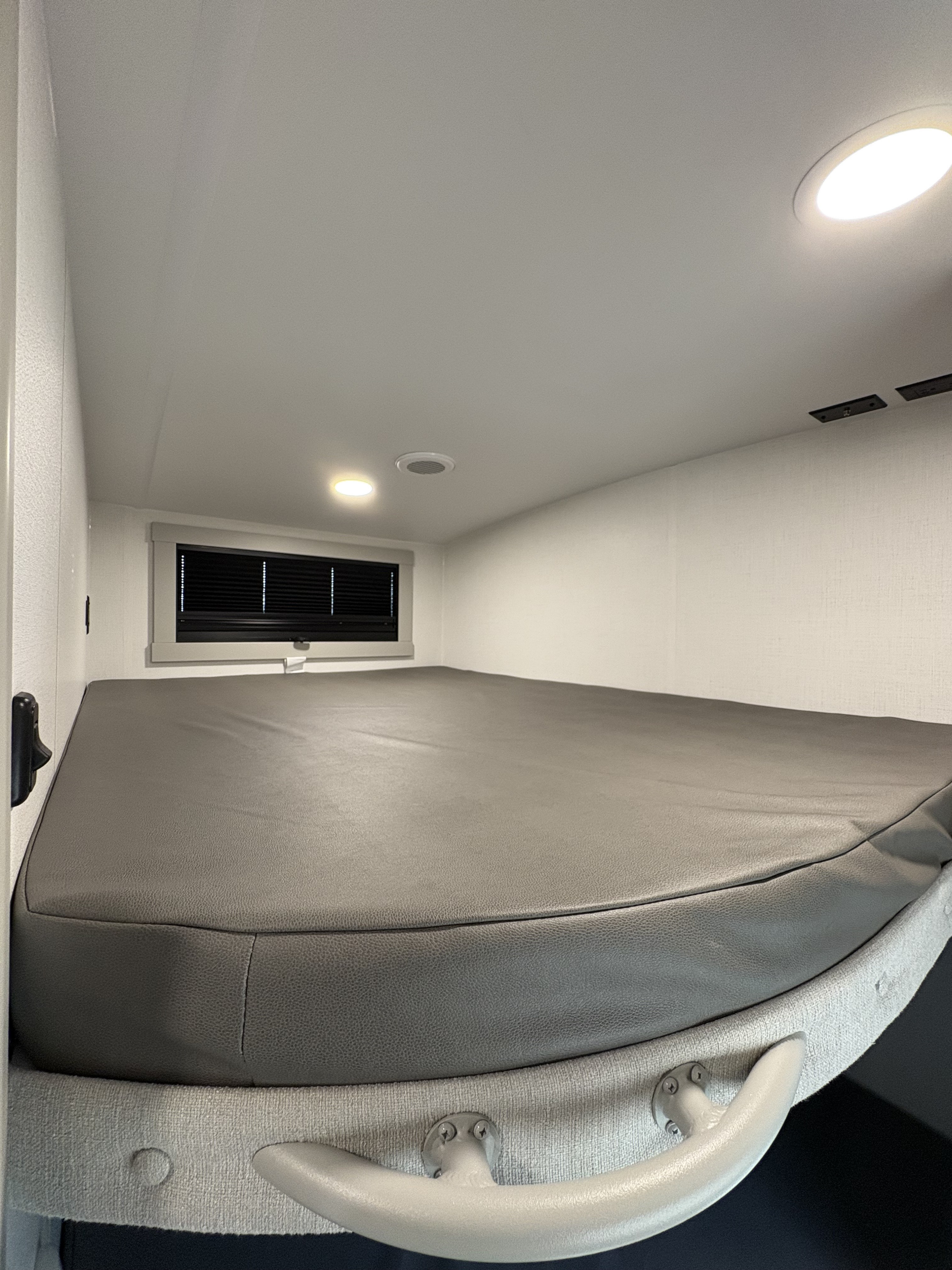 Cozy RV rental bunk bed interior with a grey mattress, window, and ceiling lights, ideal for resting.. Brinkley 295 AIR 2025