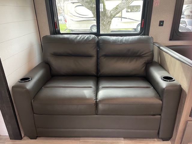 RV rental interior: A dark gray two-person sofa with built-in cup holders provides cozy seating with a view.. Jayco Jay Flight 2024