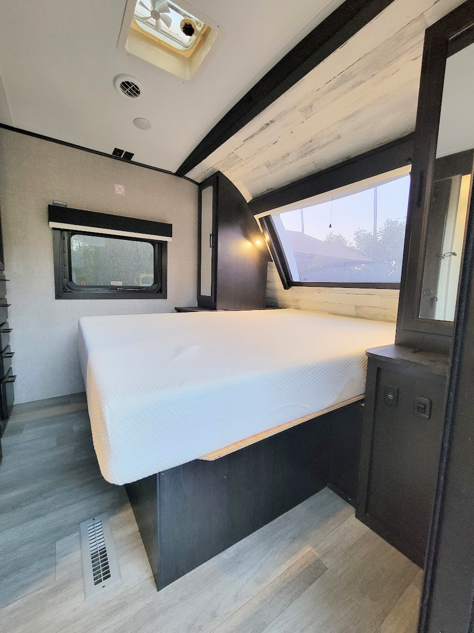 Spacious RV bedroom with a comfortable bed, large windows offering natural light, and a ceiling vent, ideal for an RV rental.. Jayco White Hawk 2022