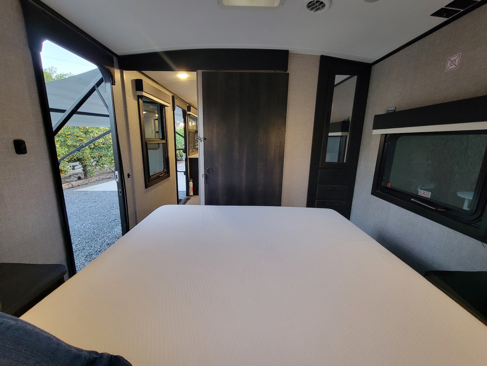 Inside a modern RV rental: a spacious bedroom with a white mattress, offering an inviting view to the outdoors.. Jayco White Hawk 2022