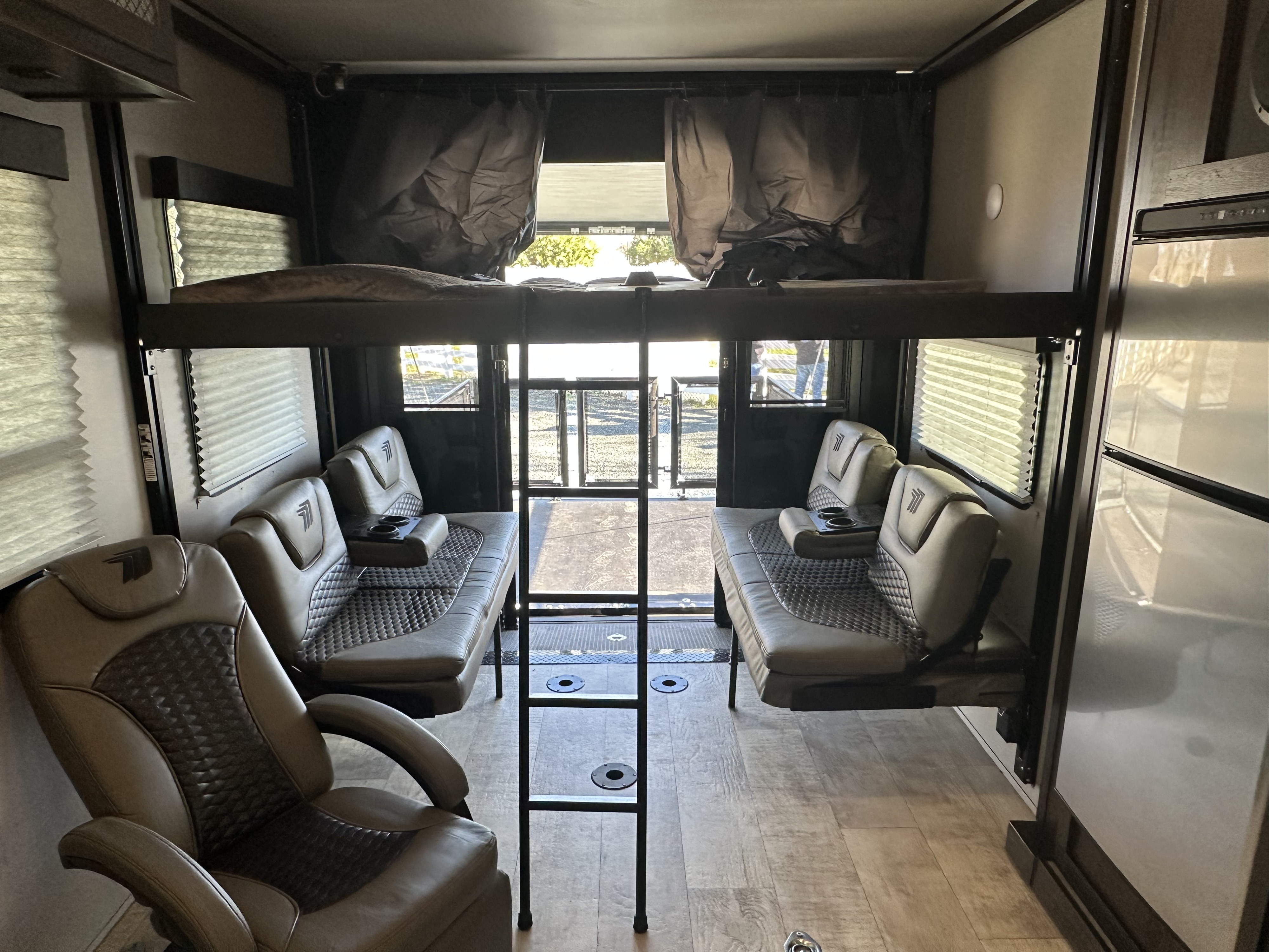 Spacious RV rental toy hauler interior with upper bunk, modular seating, and large rear ramp for gear.. Grand Design Momentum 2022