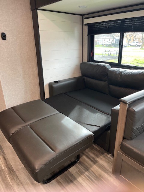 Inside this RV rental, a versatile dark sofa unfolds as a recliner or bed, optimizing comfort in the compact living area.. Jayco Jay Flight 2024