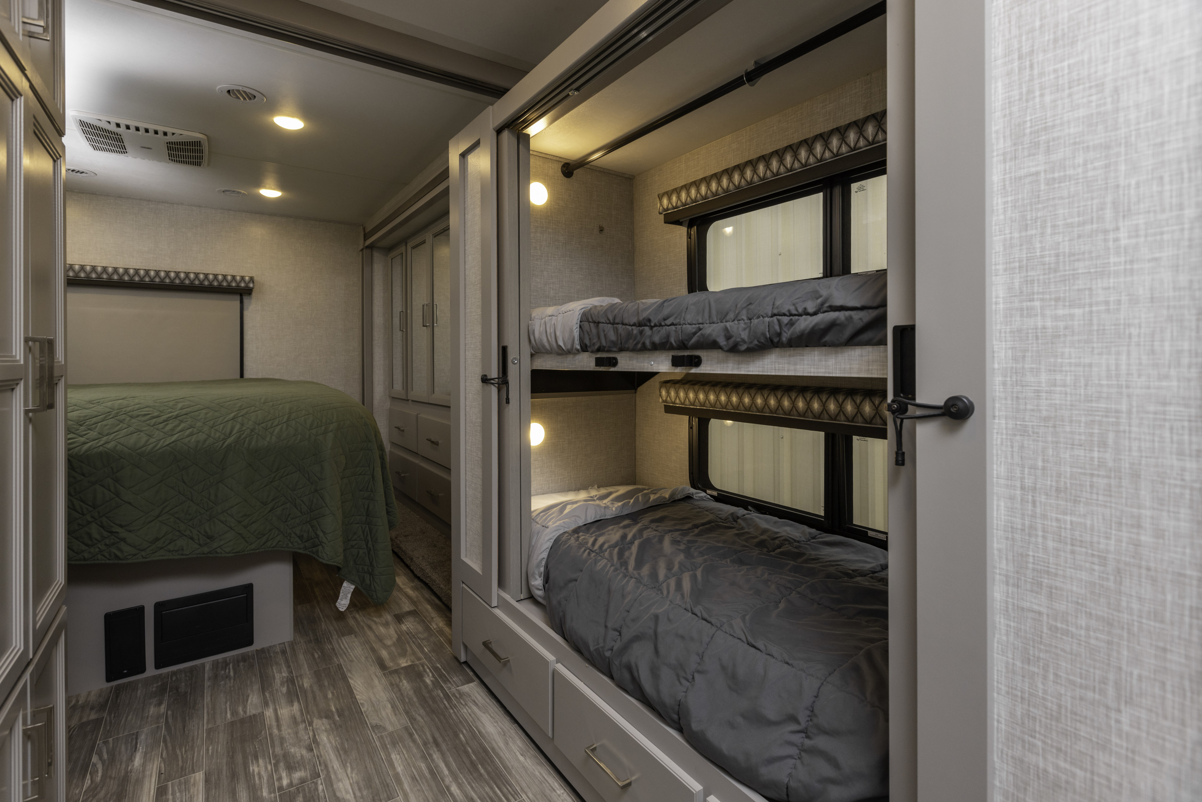RV rental interior: Master bed with green quilt & bunk beds with gray comforters. Cozy and practical family sleeping area.. Thor Hurricane 2023