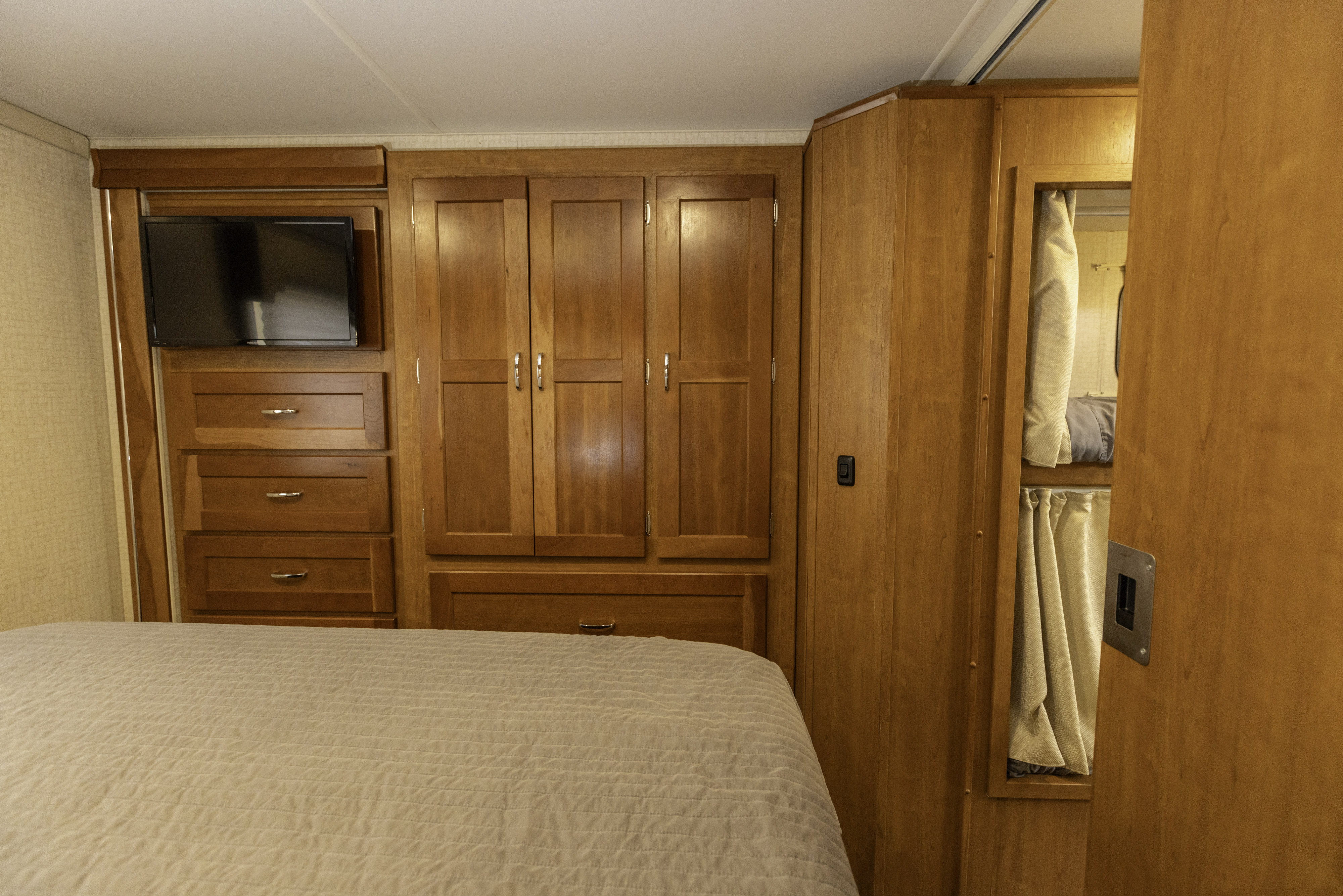 RV rental bedroom: wood cabinetry, wall-mounted TV, and cozy bunk beds, ideal for family trips.. Winnebago Spirit 2018