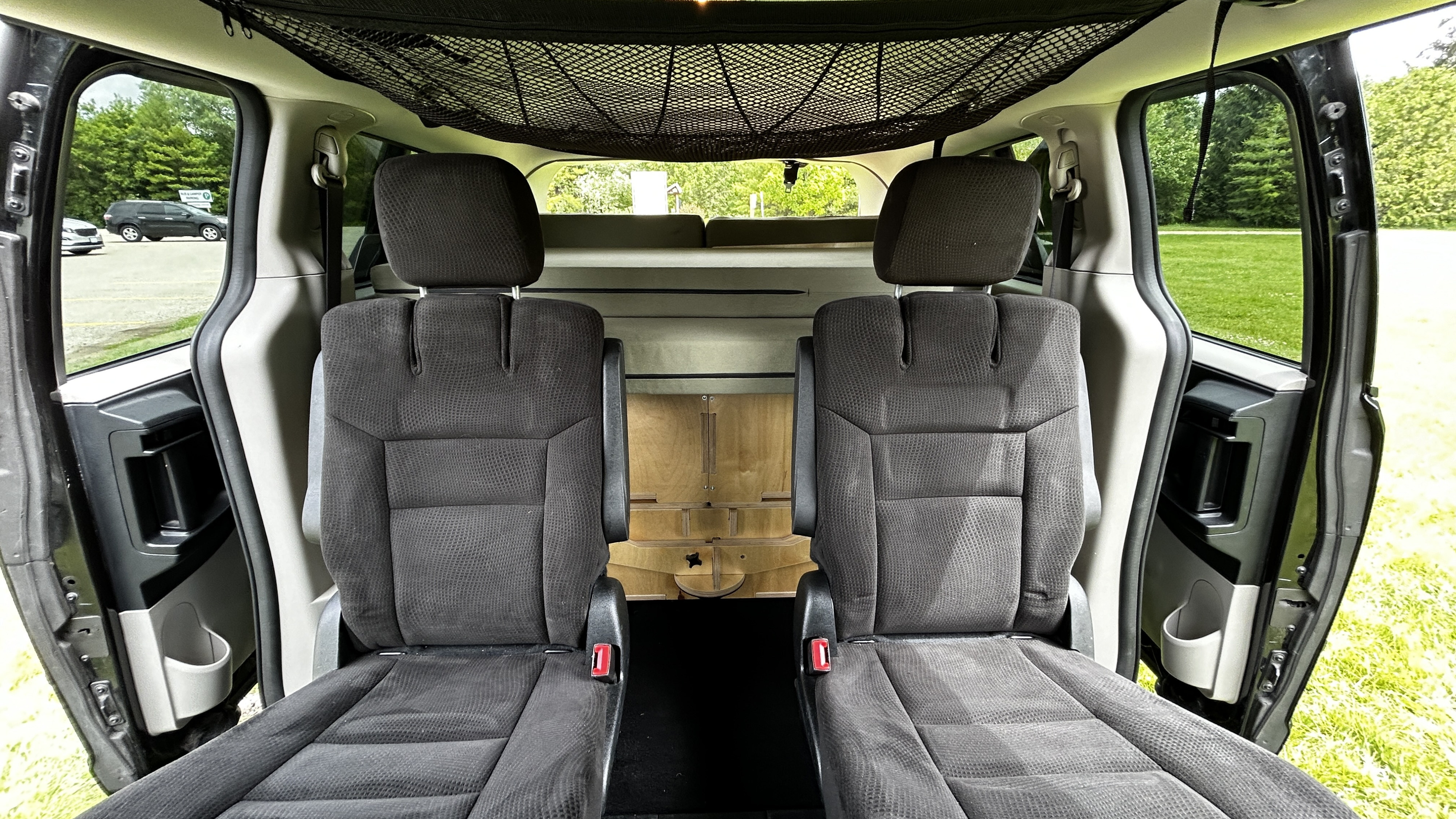 Inside an RV rental van: rear seats, overhead net, and custom bed conversion. Perfect for travel adventures.. Dodge Grand Caravan 2016