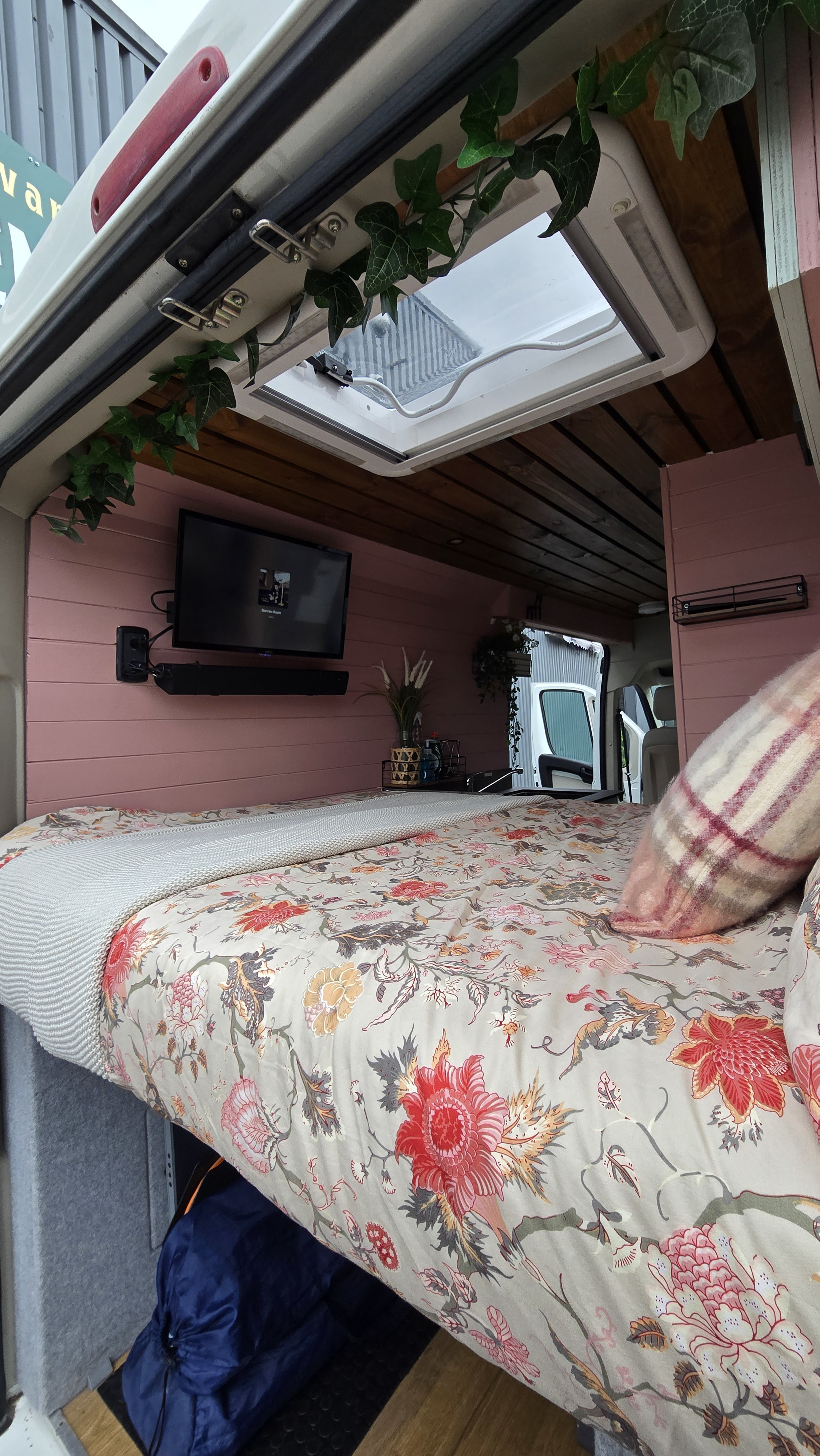 Explore this cozy RV rental's interior: floral bed, TV, skylight, and pink walls for adventures.. Citroen Relay L3H2 2017