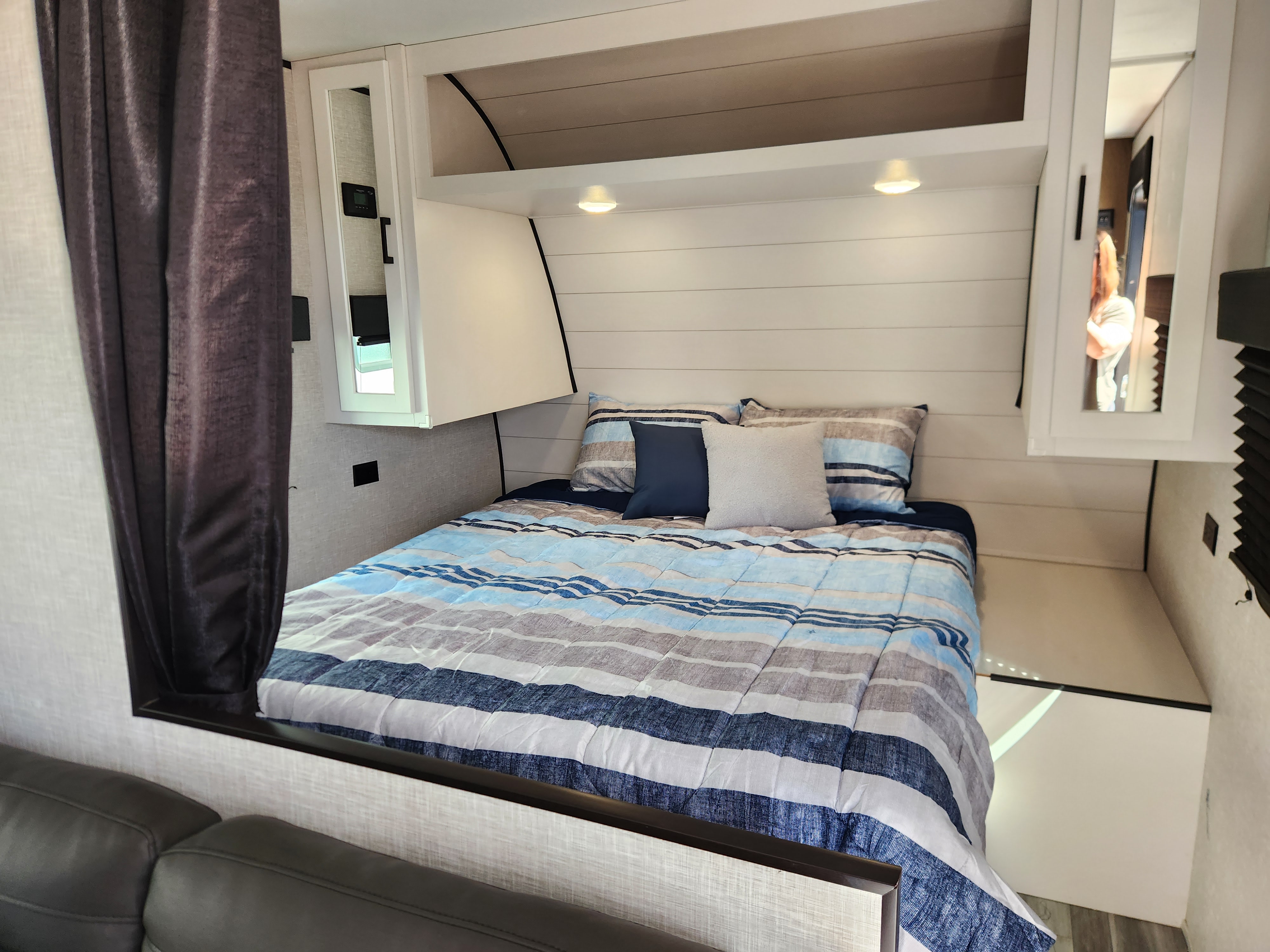 This RV rental bedroom features a bed with blue striped bedding, shiplap headboard, and mirrored storage. Bright and inviting.. Jayco Jay Flight 2024