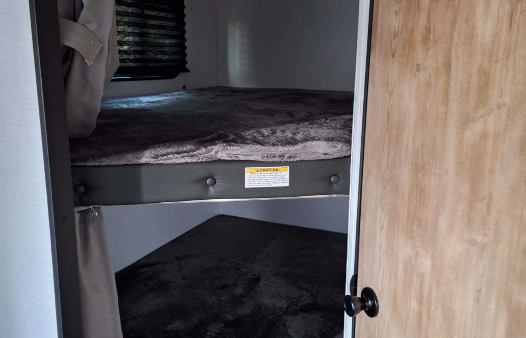 Compact RV rental sleeping area featuring cozy bunk beds, a window with blinds, and privacy curtains.. Keystone RV Springdale 2023